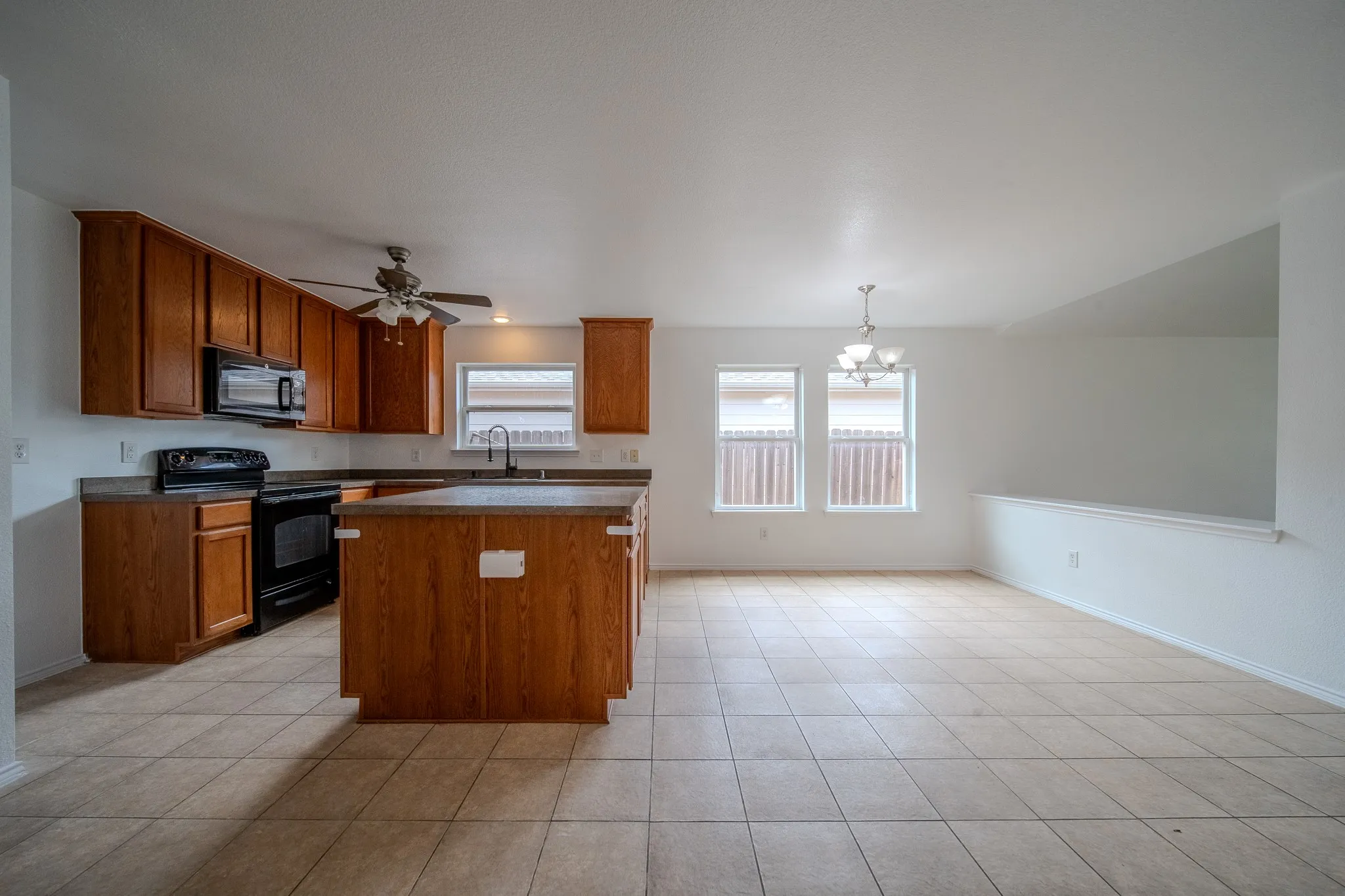 Kitchen and dining area featuring tile flooring, wooden cabinetry, a kitchen island, and a ceiling fan