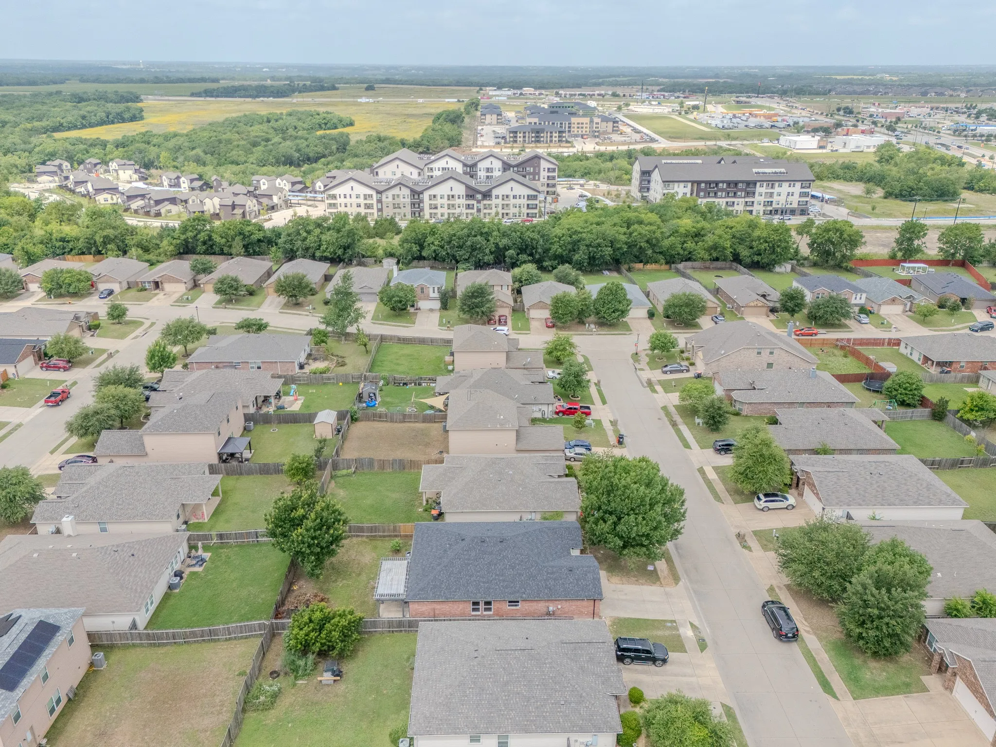 Aerial perspective showcasing a residential neighborhood with single-story homes, established trees, and paved streets