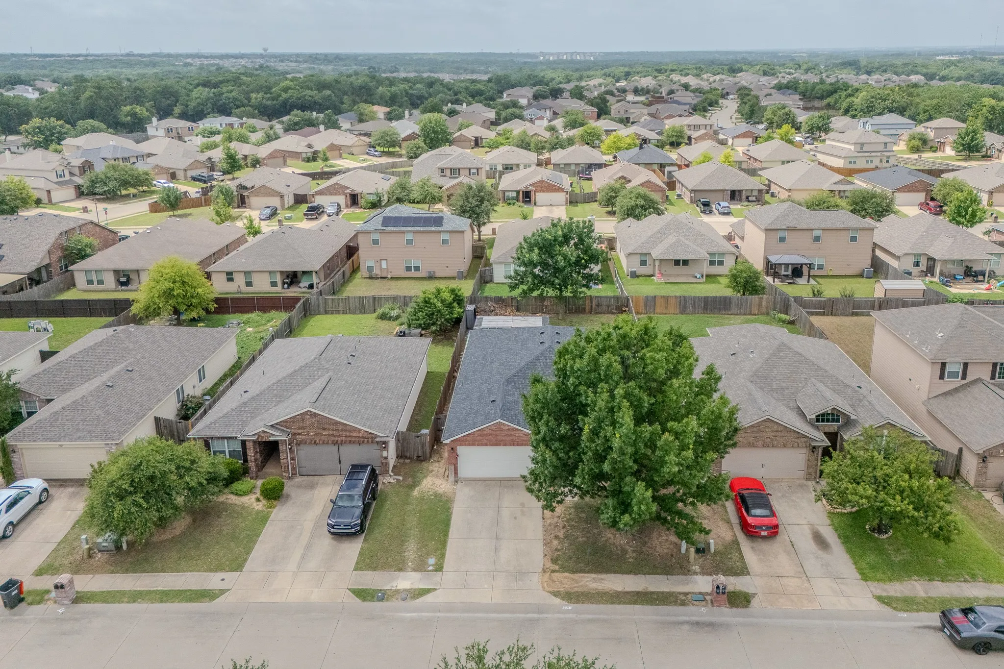 Aerial perspective of a residential neighborhood featuring single-family homes with fenced backyards