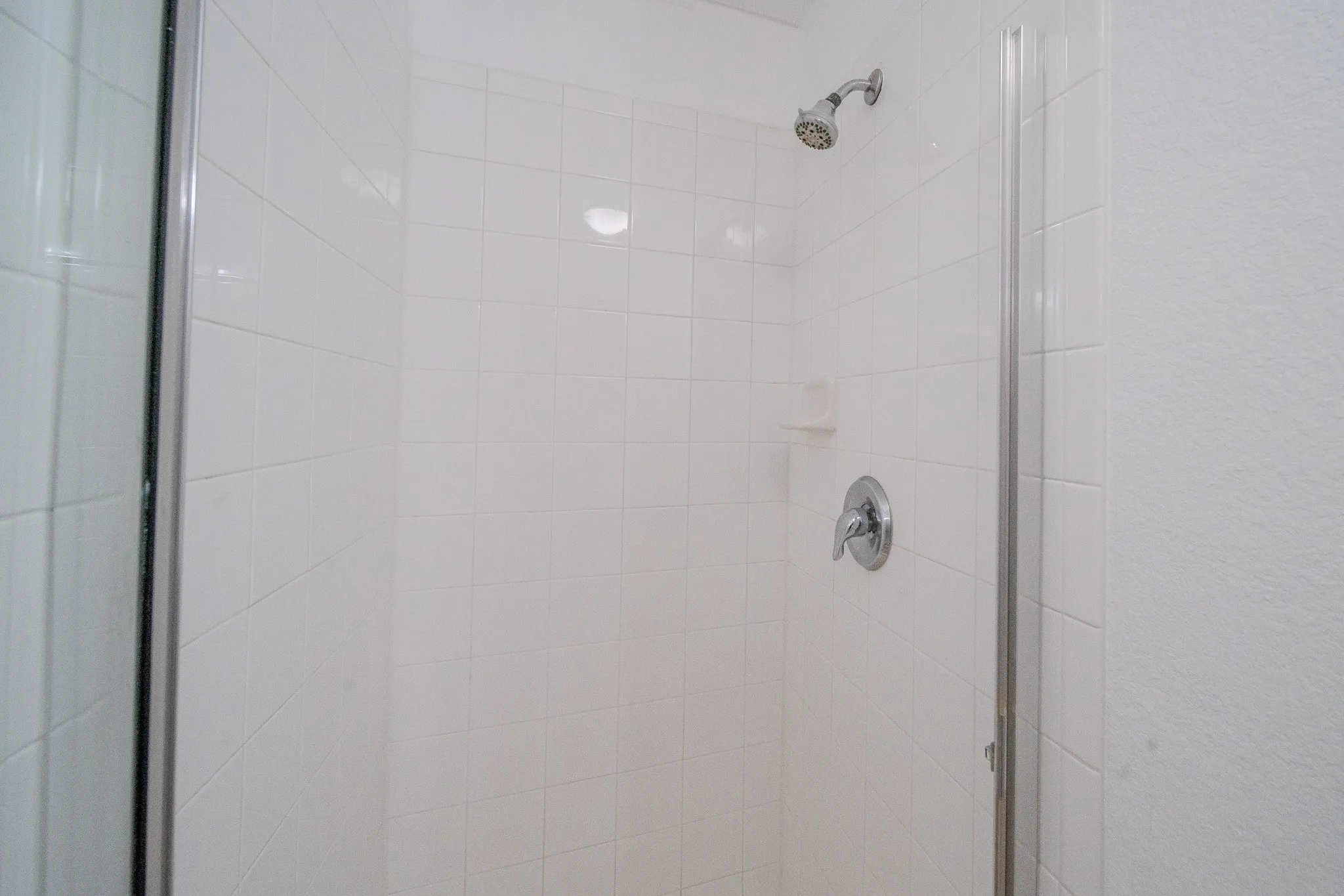 Tiled shower enclosure featuring a chrome showerhead and single-handle faucet