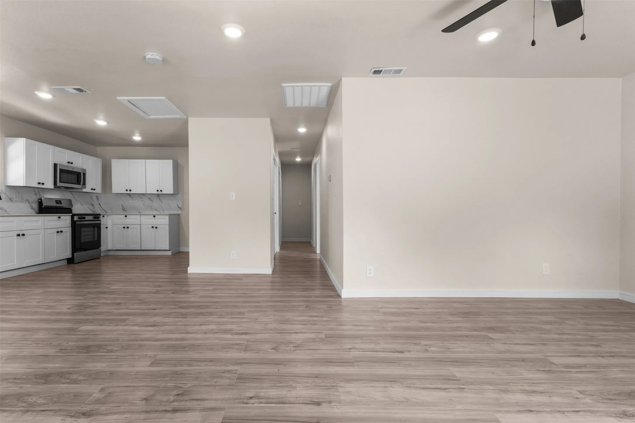 Expansive open concept living area featuring wood-finish flooring, recessed lighting, and a ceiling fan