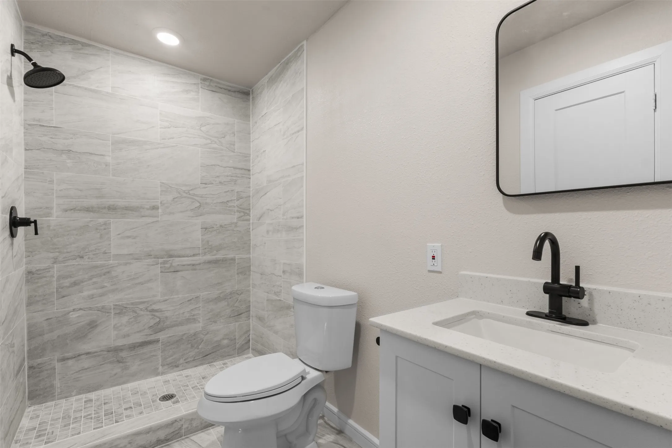 Bathroom featuring a walk-in shower with large format tile surround and pebble tile floor