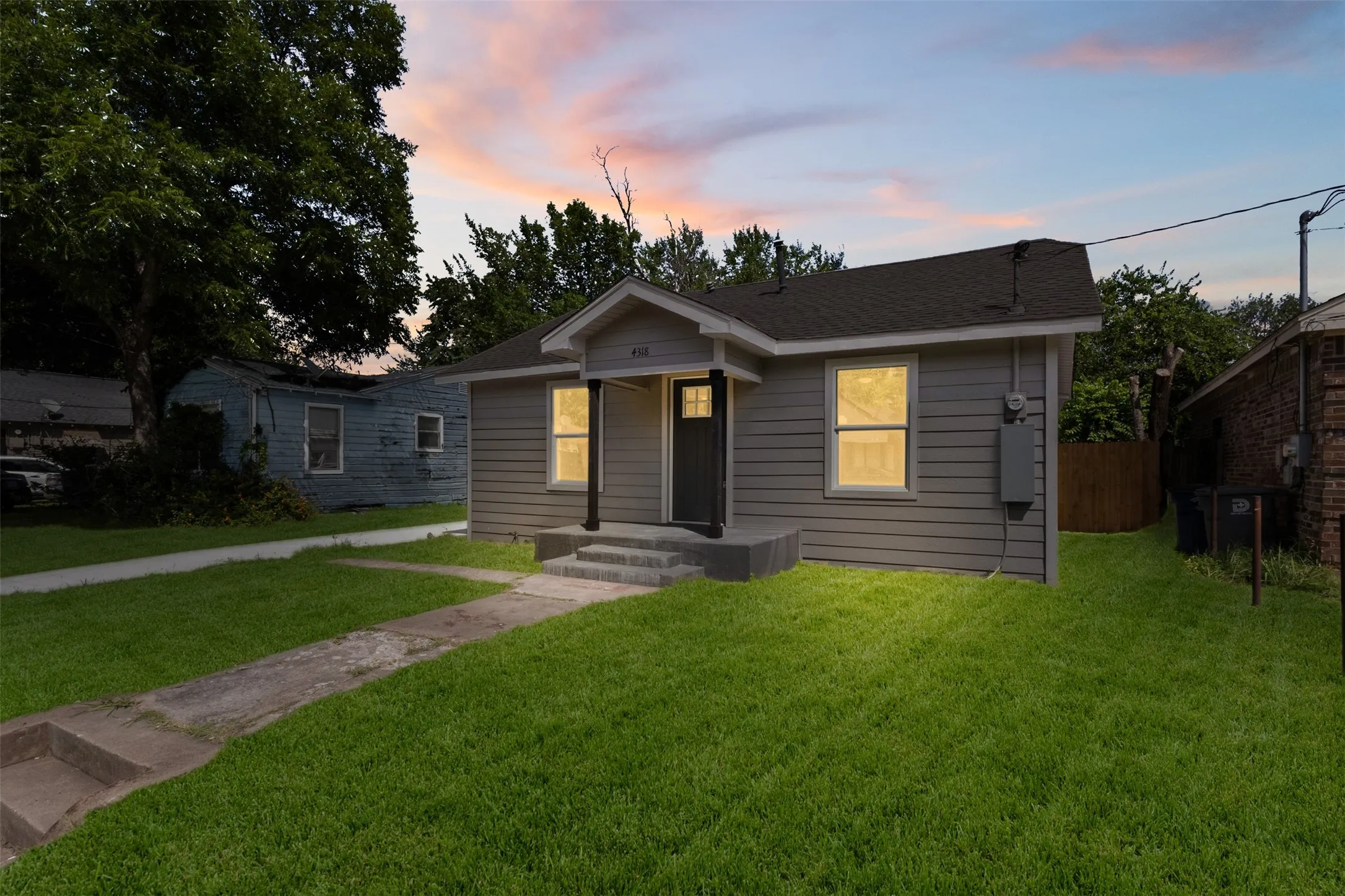 Single-story home featuring gray horizontal siding and a dark shingle roof