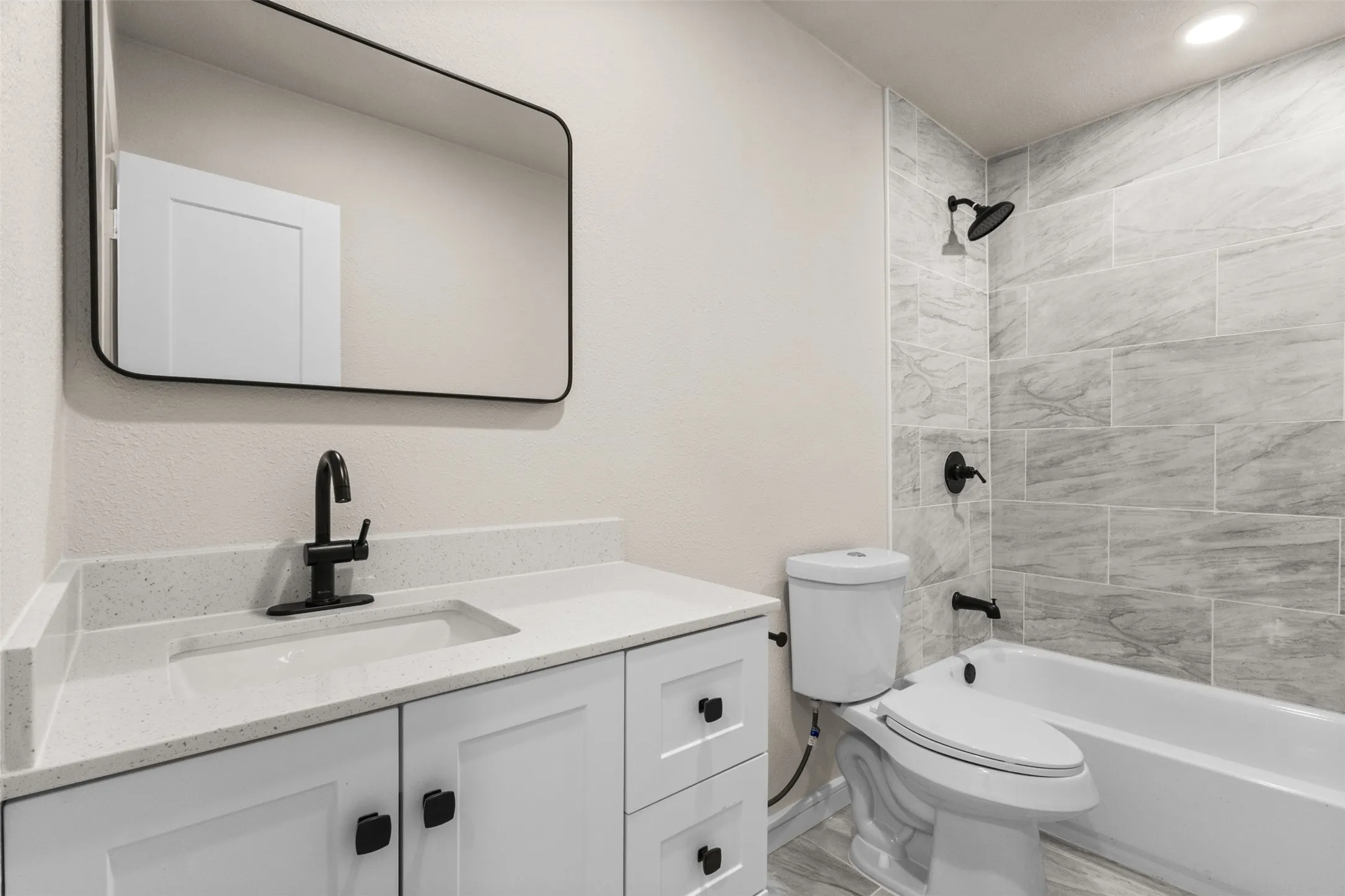 Bathroom featuring a white vanity with a light-toned countertop, rectangular undermount sink, and matte black faucet