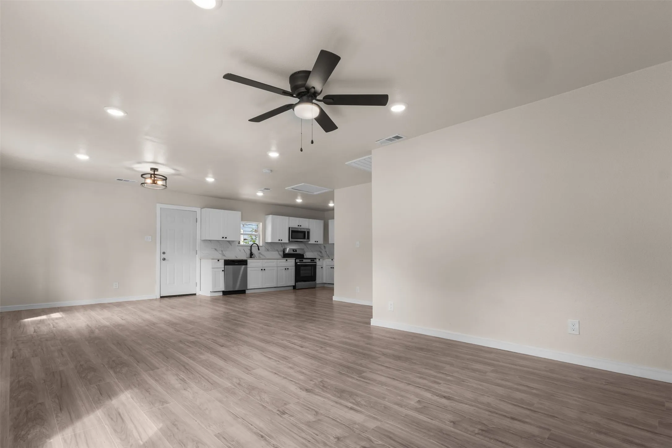 Open-concept living area featuring wood-finish flooring and a ceiling fan