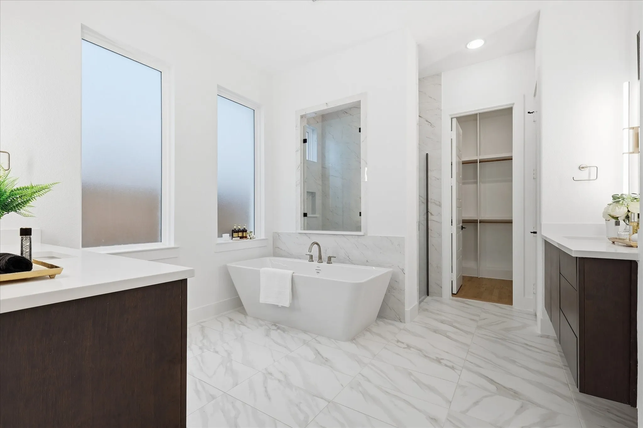 Freestanding soaking tub complemented by white marble-look tile flooring and wainscoting