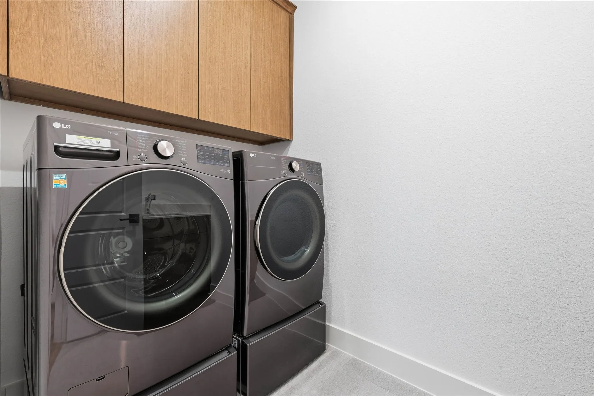 Laundry area featuring wood-finish cabinetry and a neutral color palette