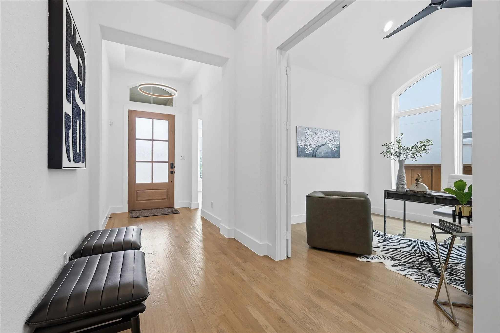 Foyer entry featuring wood-finish flooring, a wood-paneled door with frosted glass inserts, and a contemporary circular pendant light
