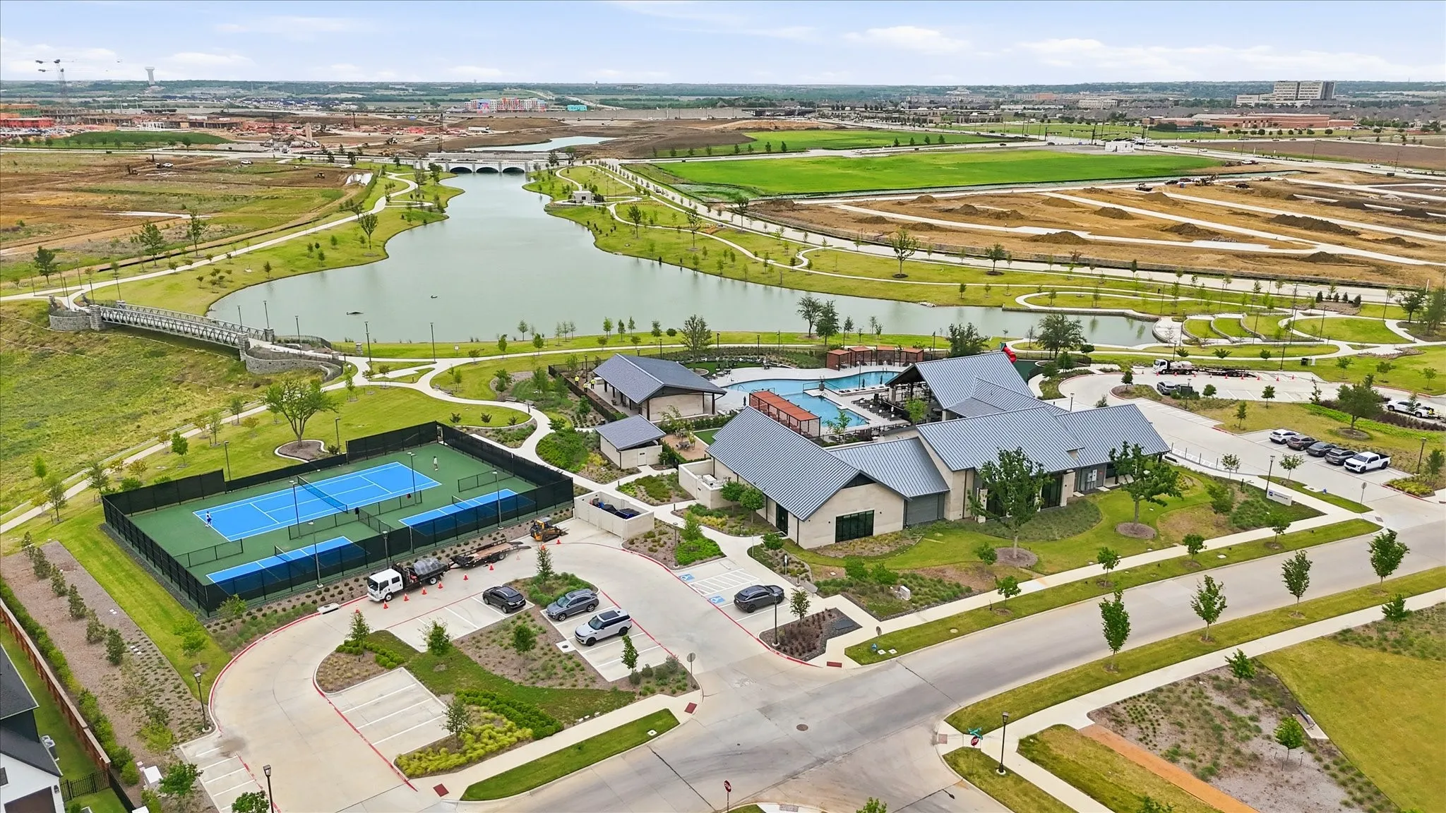 Community amenities featuring a modern clubhouse, swimming pool, tennis courts, and a scenic lake with walking paths