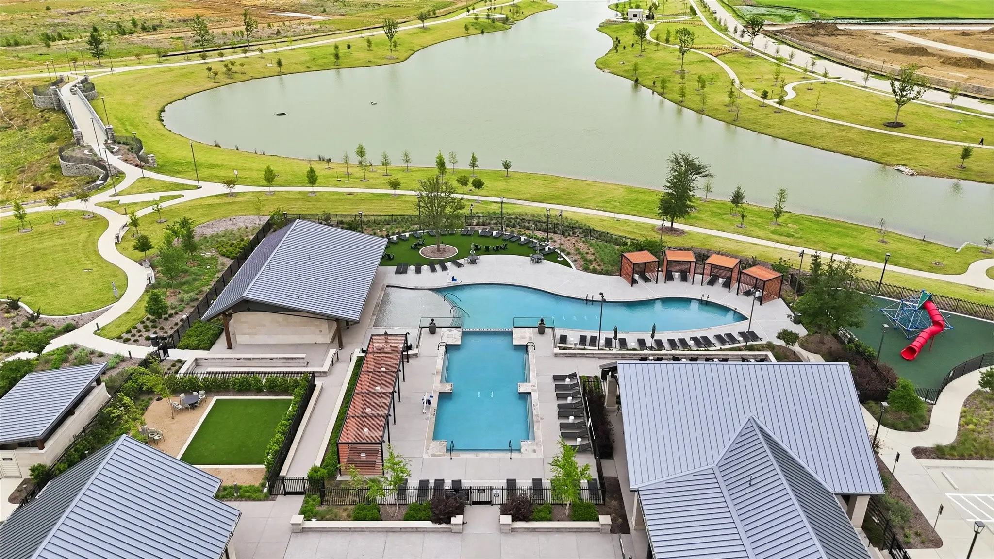 Expansive community amenity center featuring multiple swimming pools, a playground, and covered cabanas
