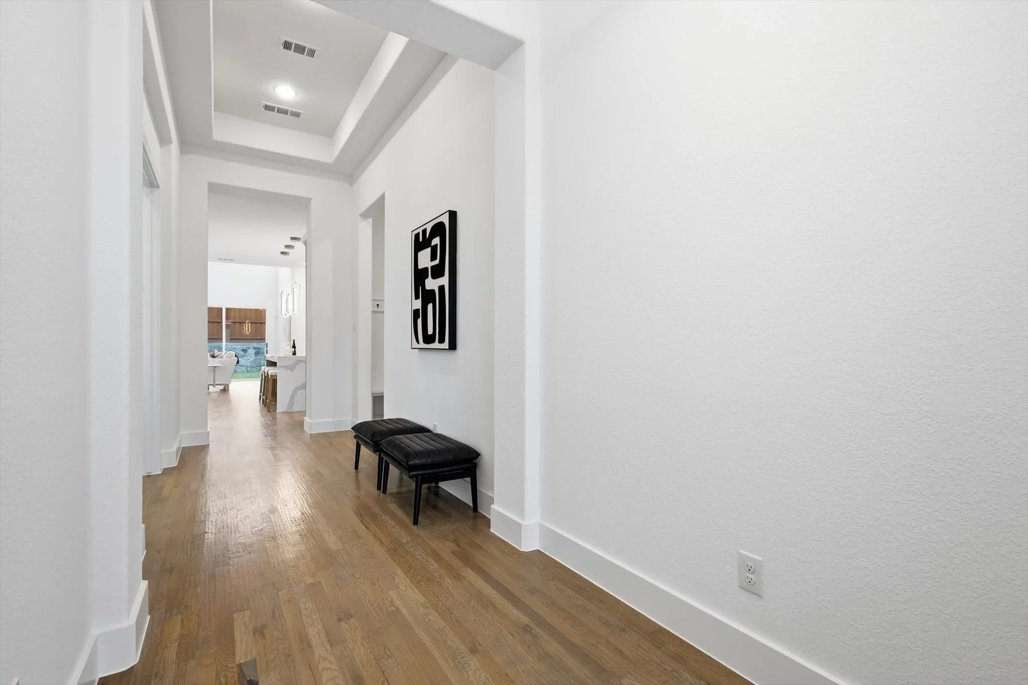 Entryway hallway featuring recessed lighting, wood-finish flooring, white baseboards, and a tray ceiling