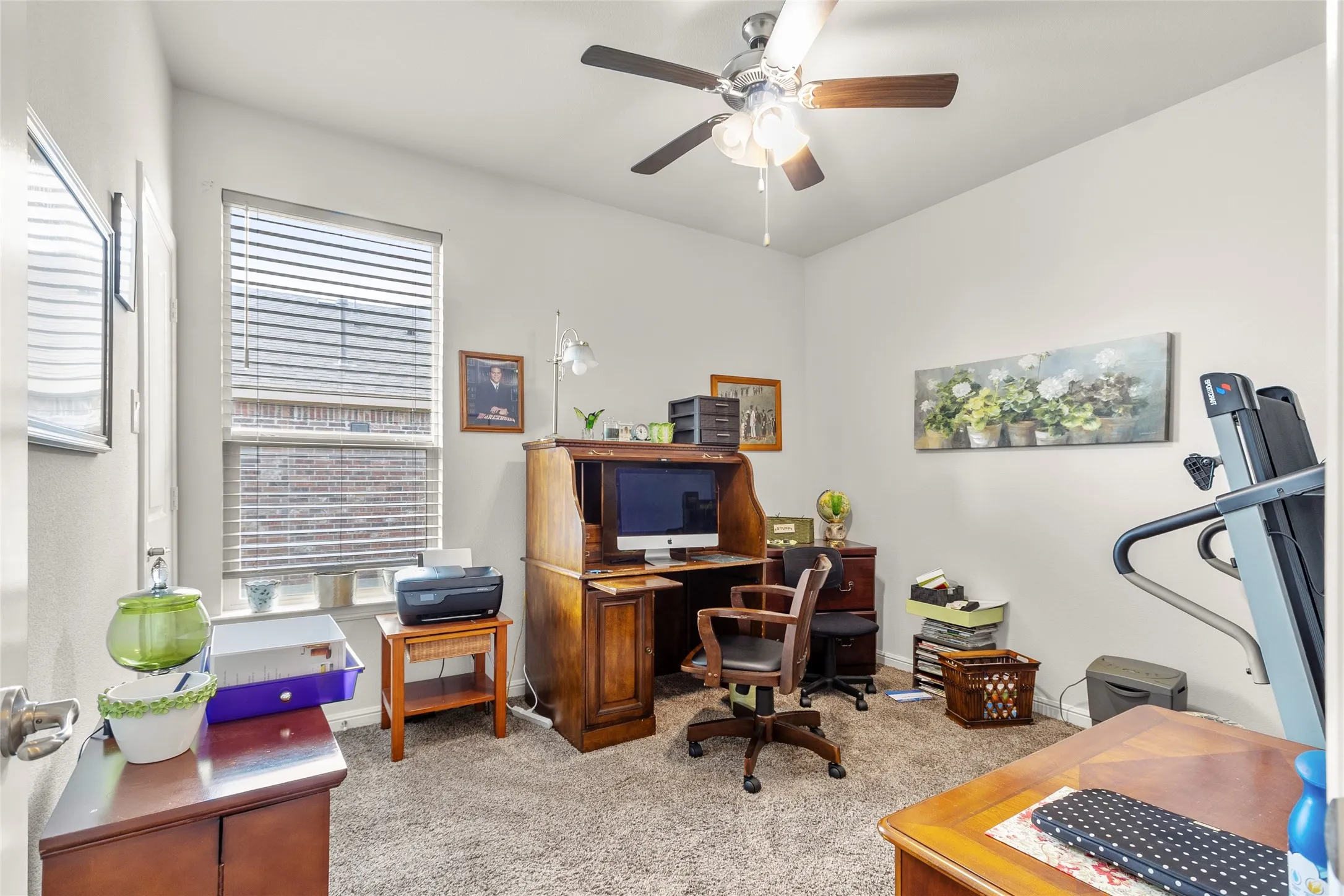 Carpeted interior room featuring a window with blinds, a ceiling fan with light fixture, and light-colored wall paint