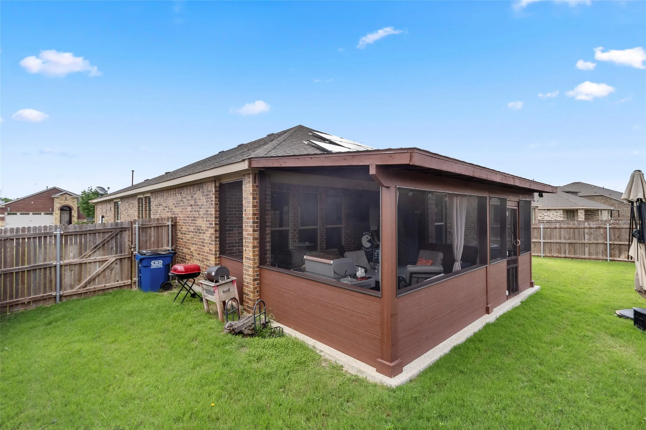 Expansive backyard featuring a screened-in porch with a solid panel base and a wood fence enclosure