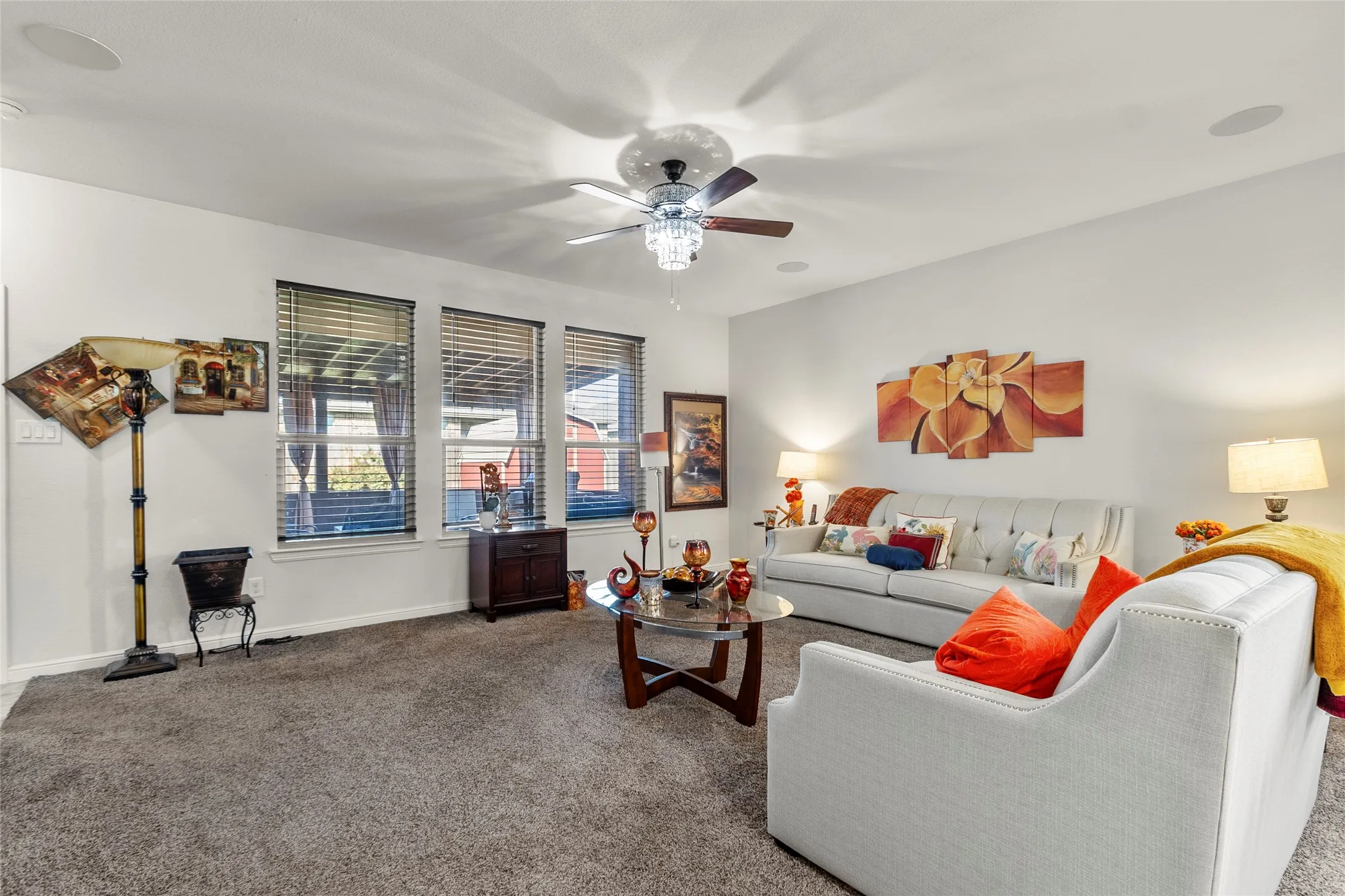 Living room featuring a chandelier-style ceiling fan, recessed lighting, and integrated ceiling speakers