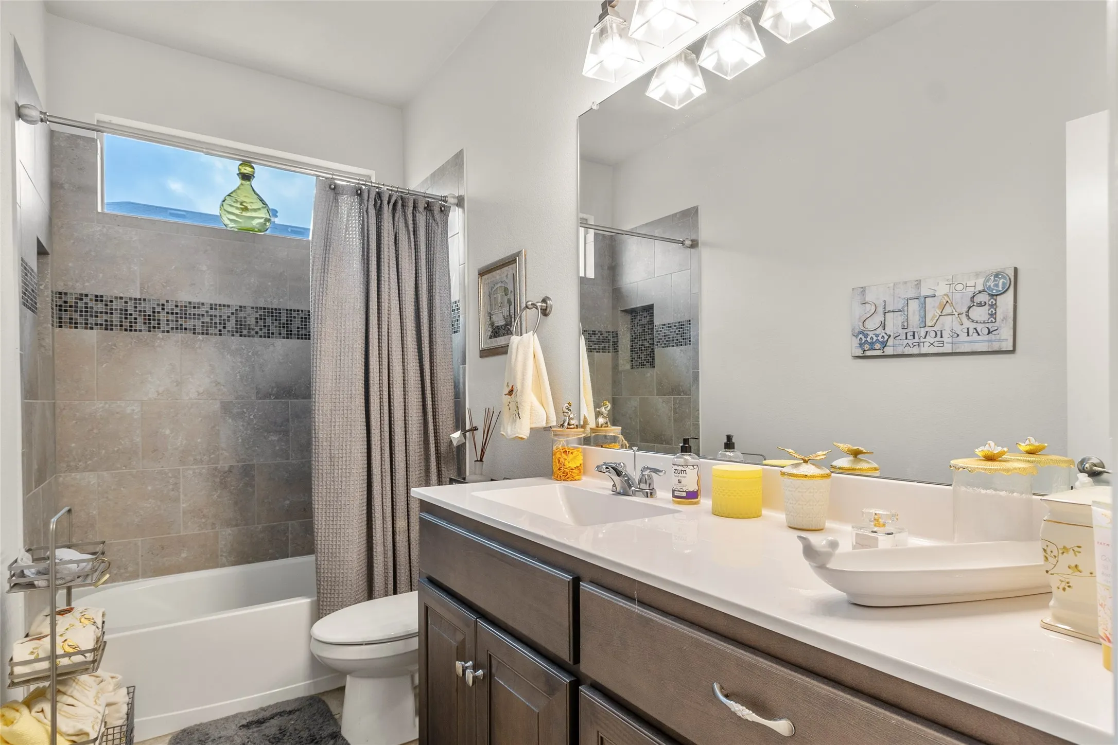 Bathroom featuring a wide vanity with a solid surface countertop, a single undermount sink, and a large wall-mounted mirror