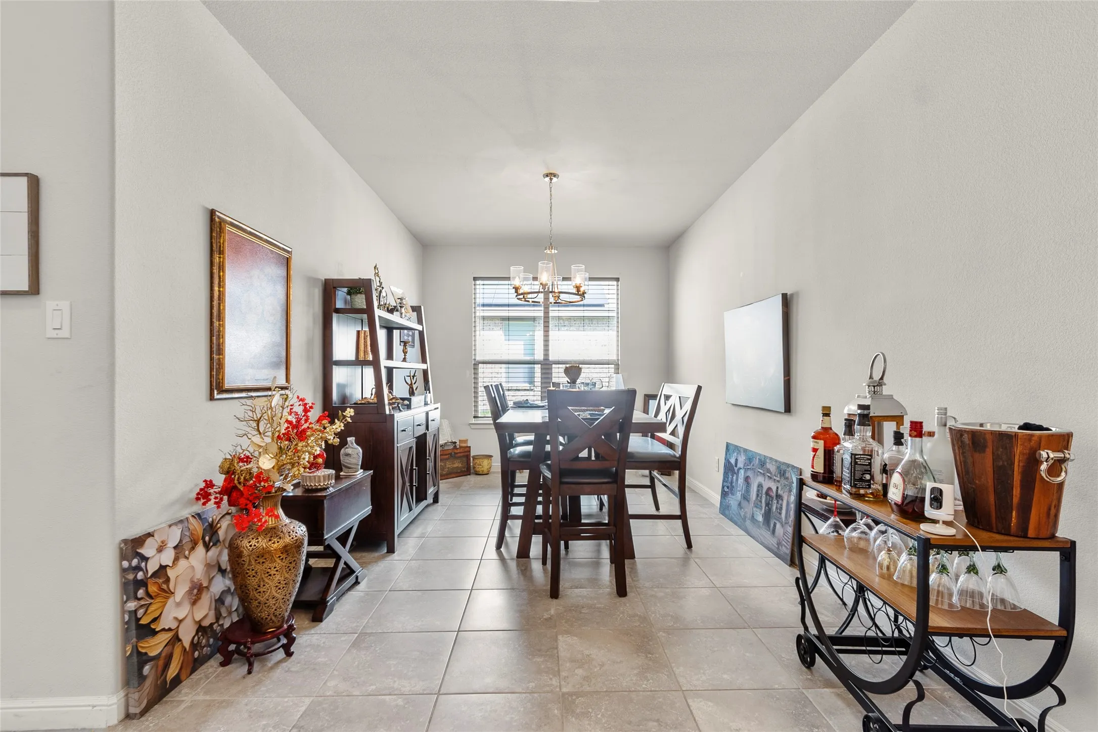 Spacious dining area featuring neutral wall tones, tile flooring, and a chandelier light fixture