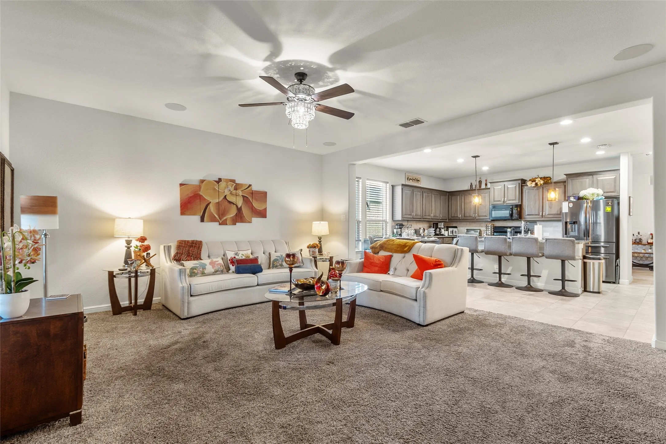 Spacious living area with an open concept design, featuring an elegant ceiling fan with a crystal light fixture