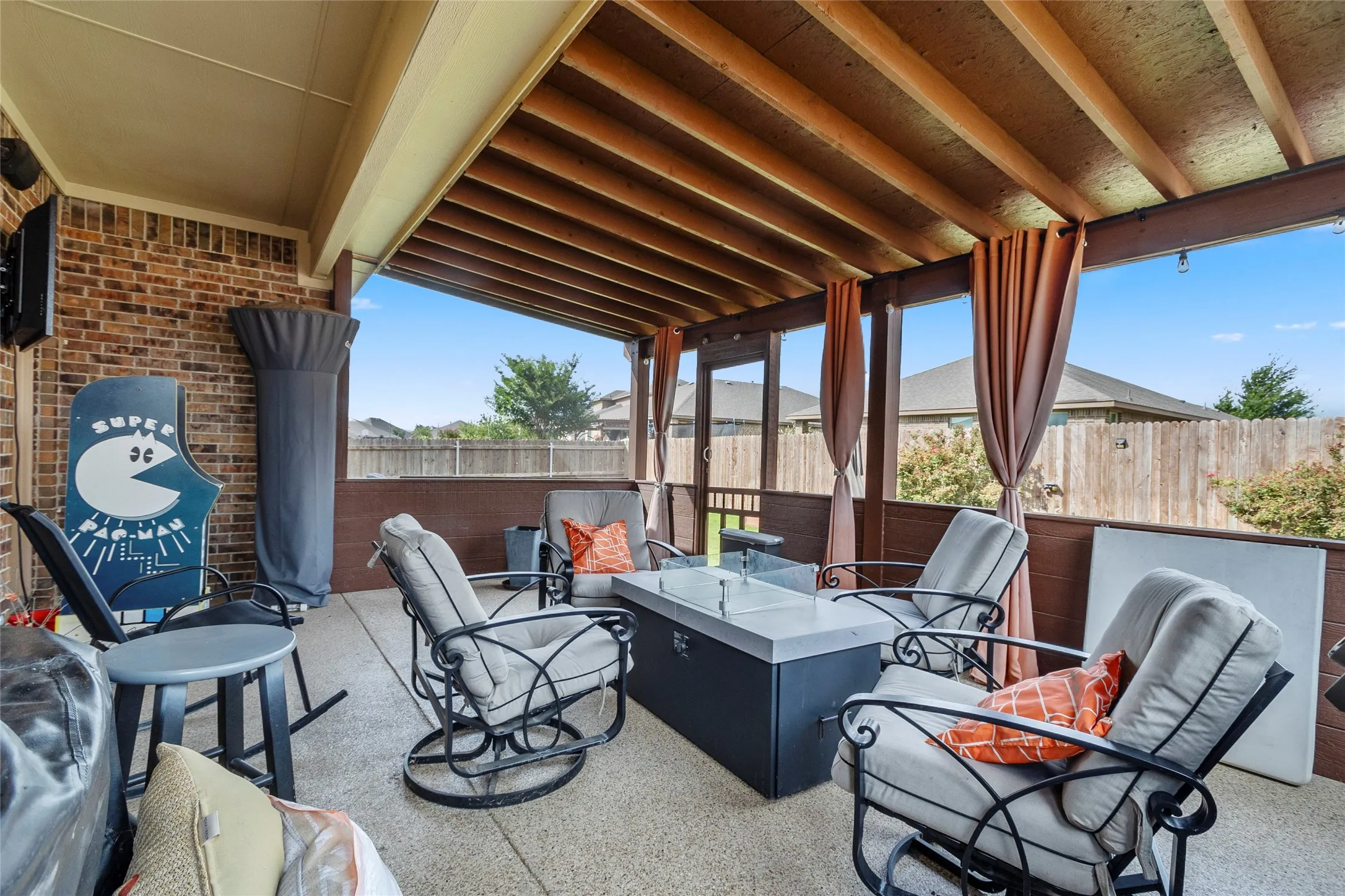 Screened patio featuring a wood-beam ceiling, brick exterior wall, concrete flooring, and an outdoor fire pit
