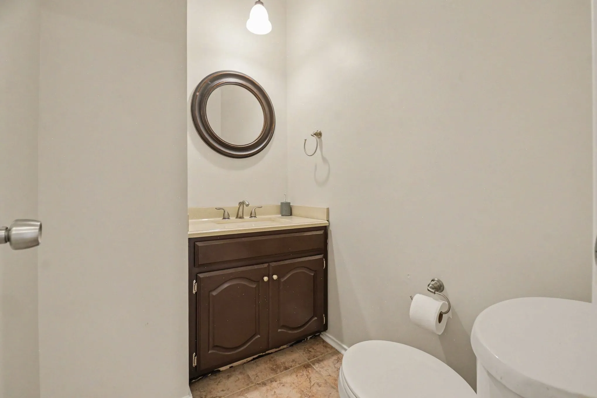 1st floor powder room featuring a dark wood-finish vanity with a light countertop, an oval mirror, and a wall-mounted light fixture