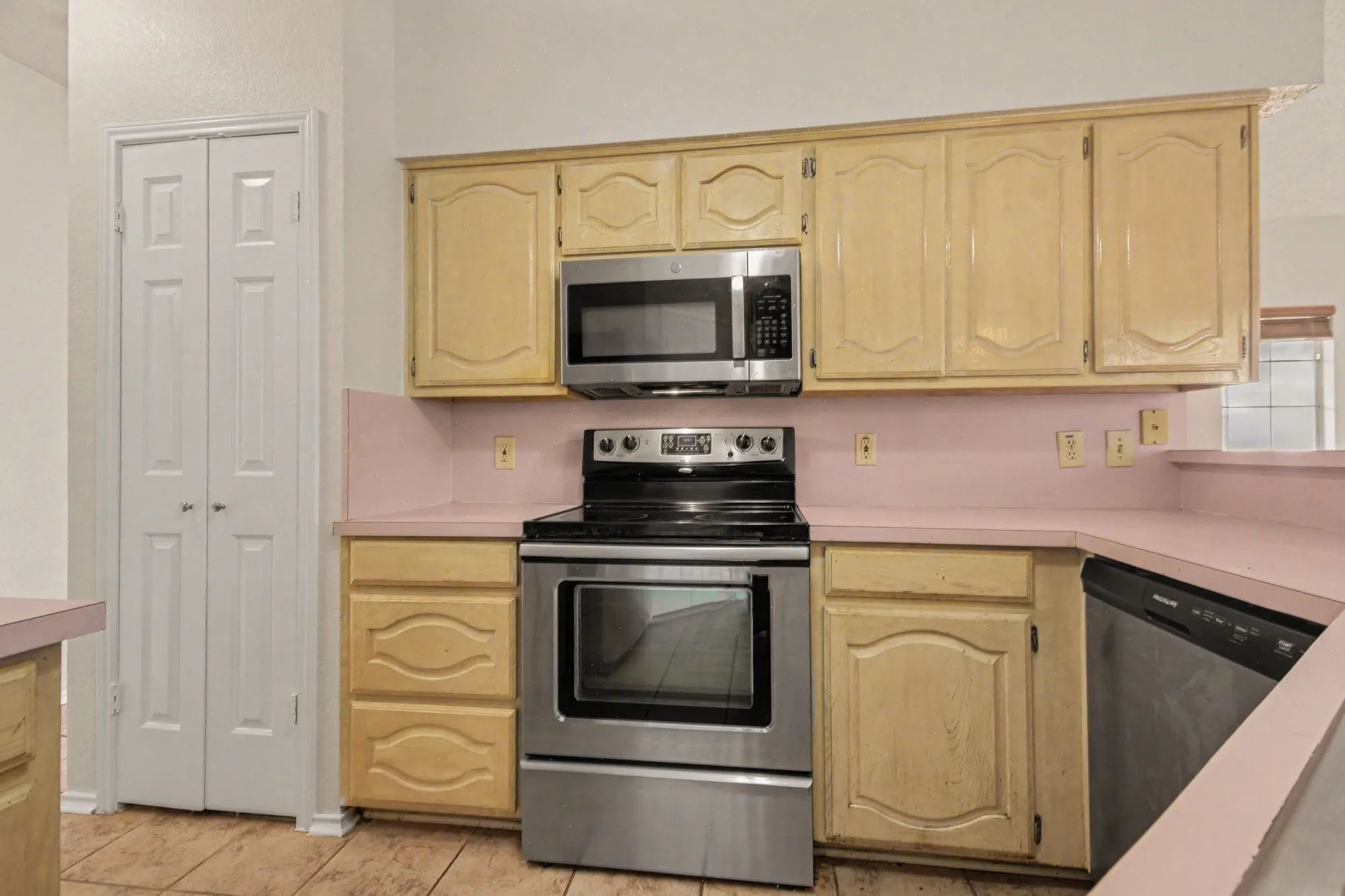 Kitchen featuring light-finish cabinetry, stainless steel range, built-in microwave, and a black dishwasher