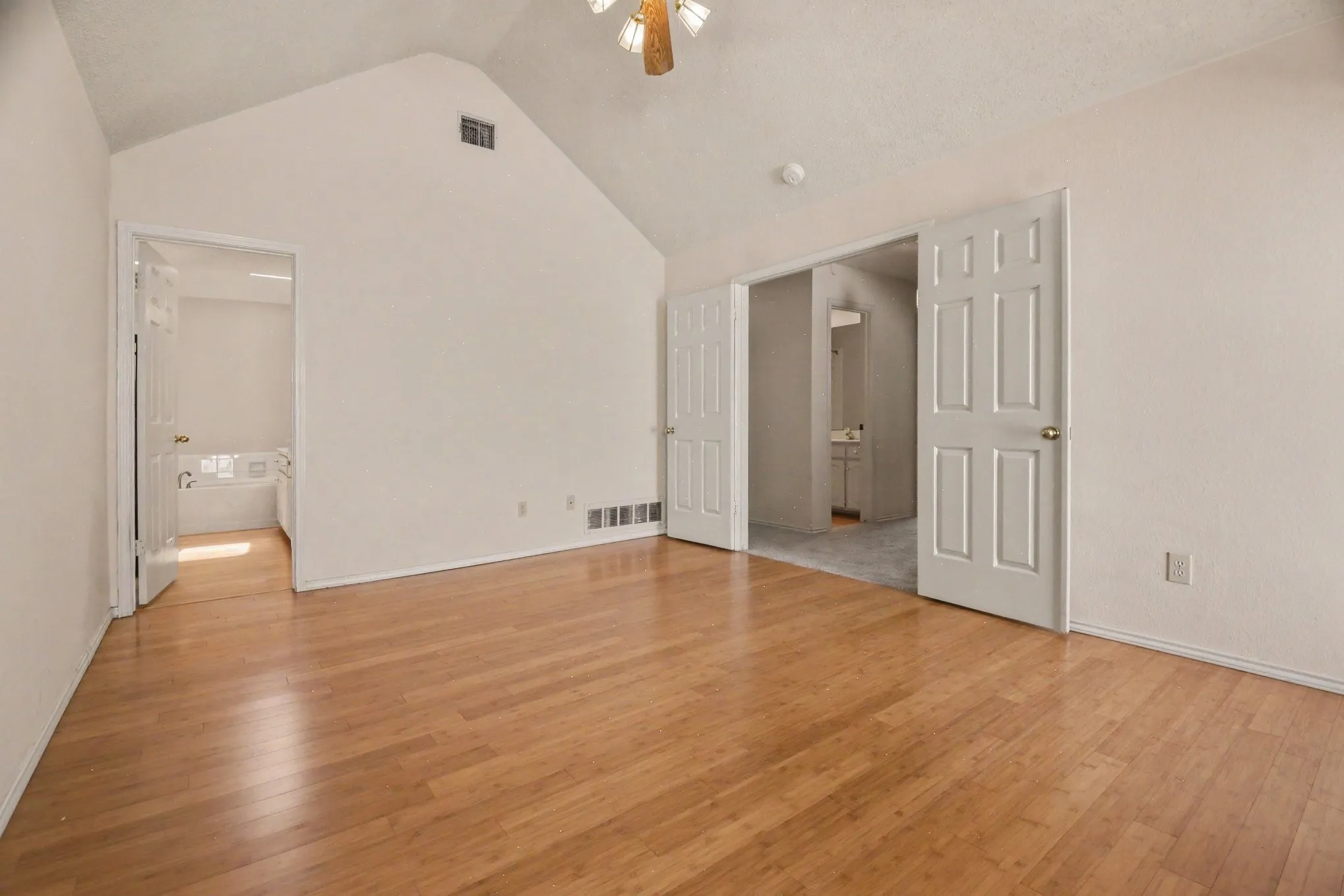 The owner's suite offers spacious room featuring vaulted ceilings, wood-finish flooring, and white paneled doors