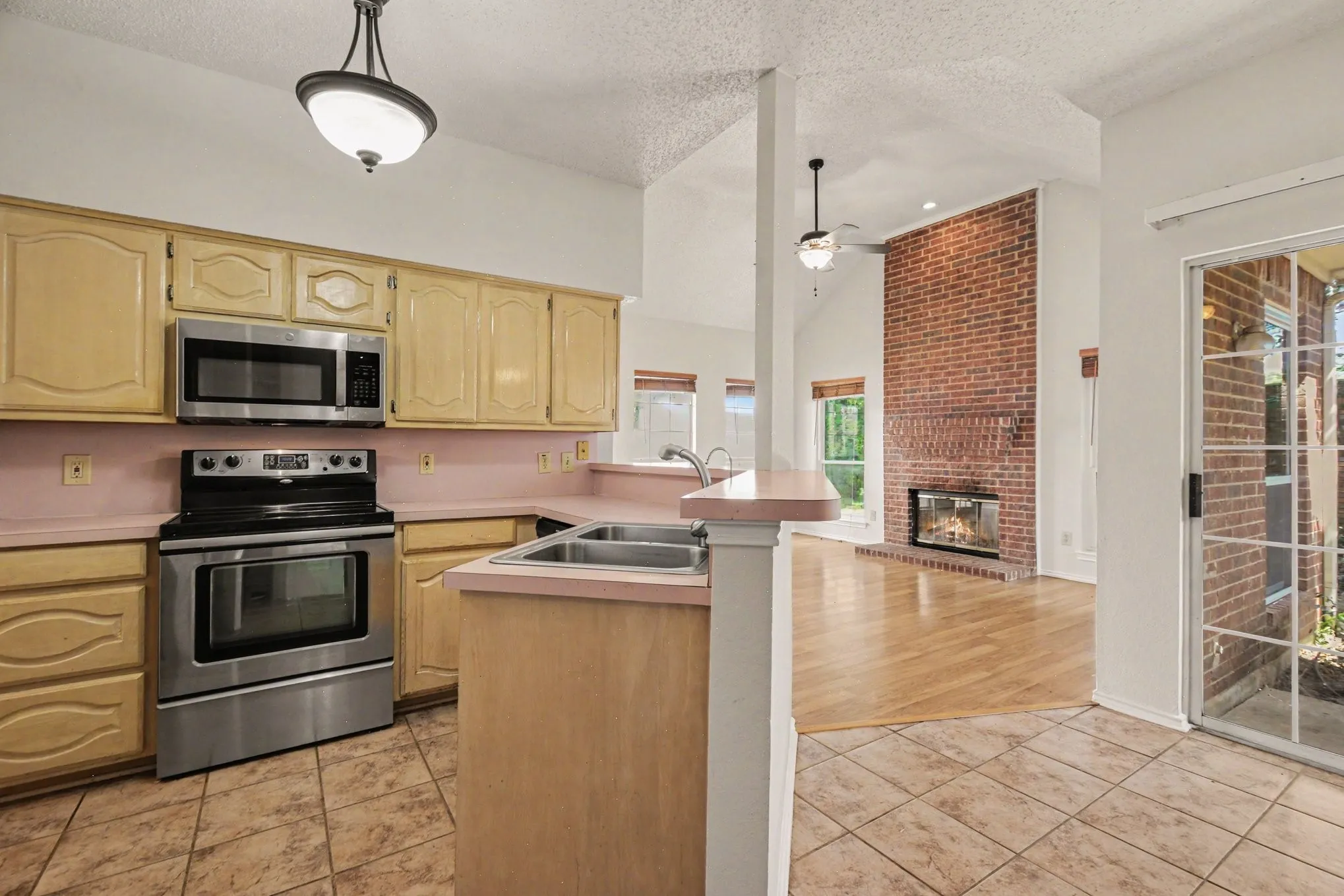 Kitchen featuring light wood-finish cabinetry, stainless steel appliances, and tile flooring