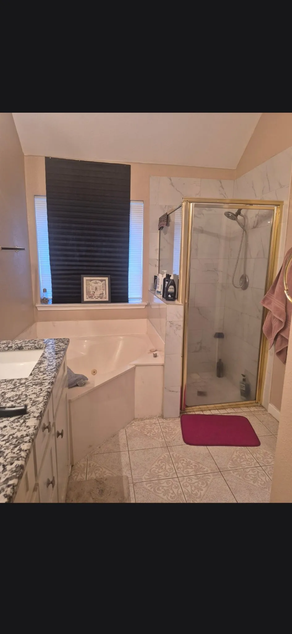 Bathroom featuring a built-in jetted tub, a separate shower with a glass enclosure, a vanity with a granite-style countertop, and tiled flooring