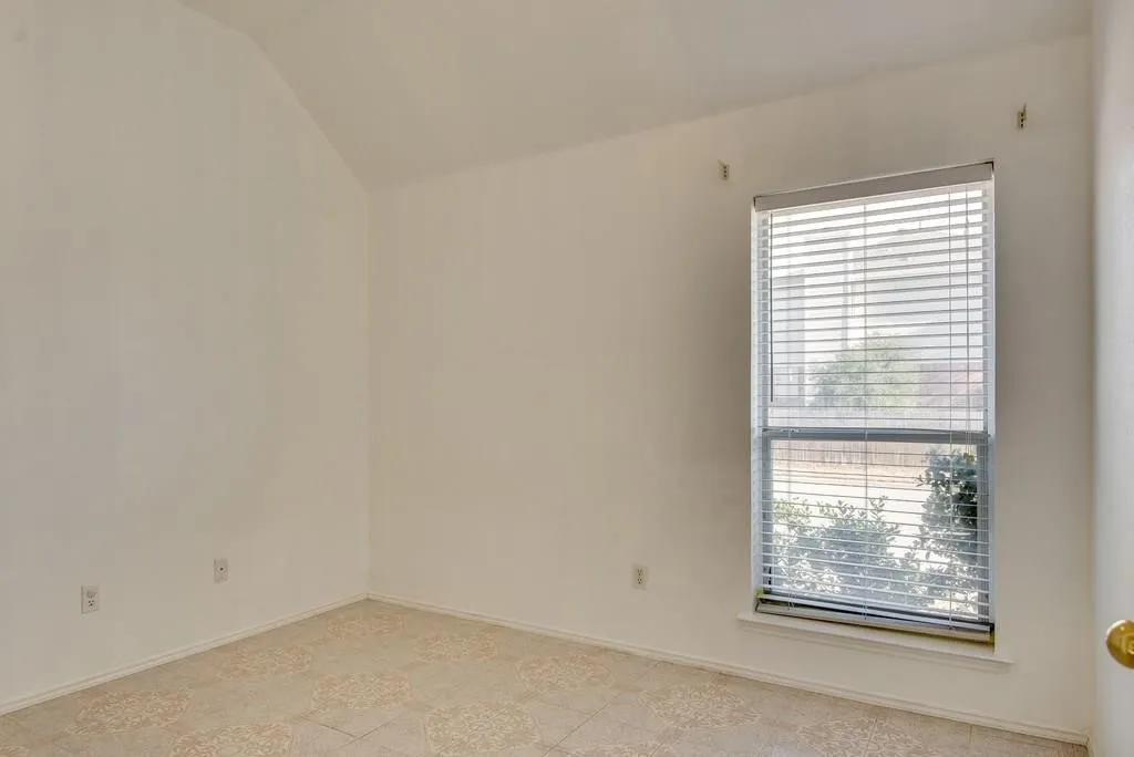 Angled ceiling room with a single window featuring horizontal blinds