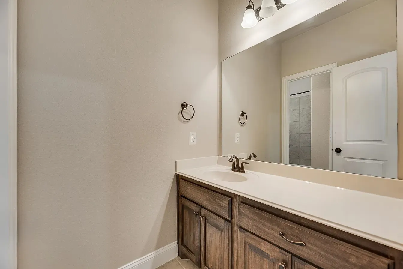 Bathroom vanity featuring a single undermount sink, a white countertop, dark wood-finish cabinetry, and a large wall-mounted mirror with overhead lighting