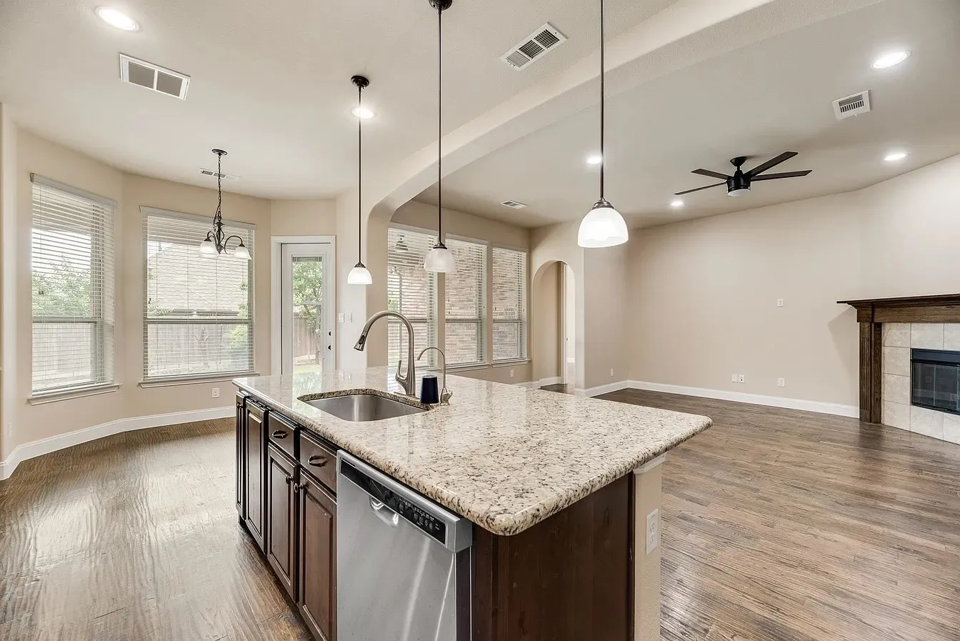 Kitchen island featuring a granite countertop, undermount sink, and stainless steel dishwasher
