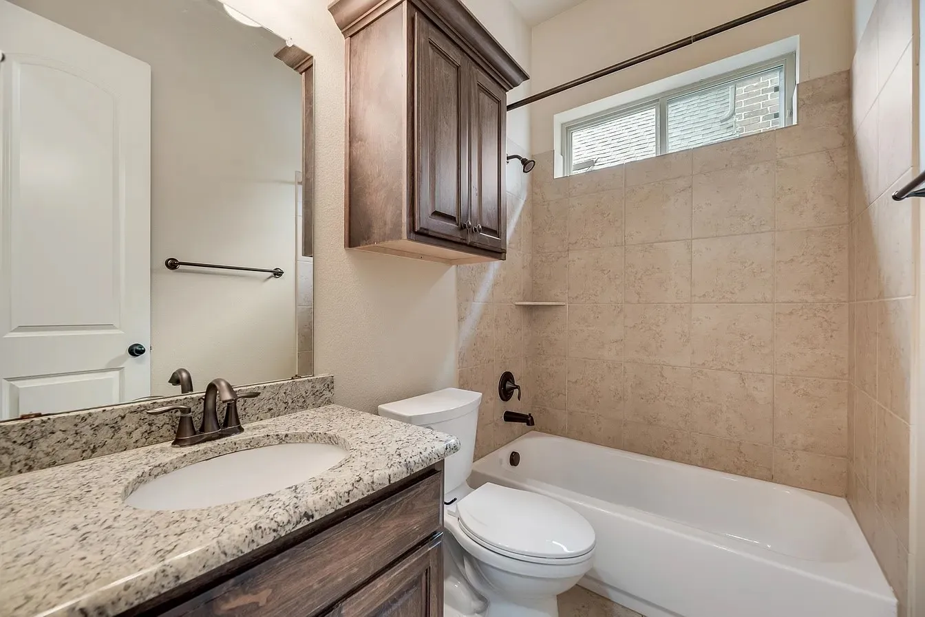 Bathroom featuring a single vanity with a speckled countertop, undermount sink, and dark bronze-finish fixtures