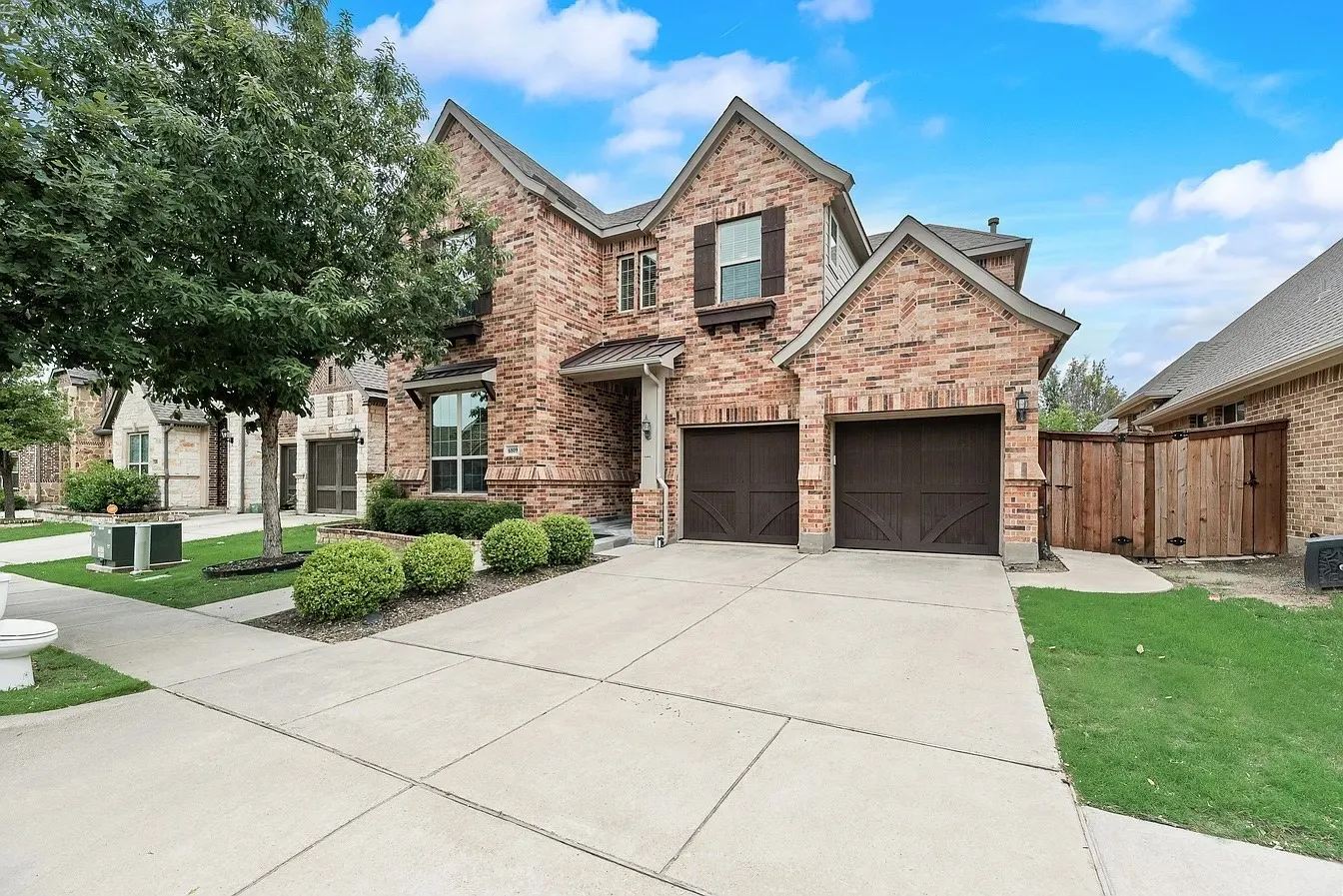 Brick exterior featuring a gabled roofline and a two-car garage with carriage-style doors