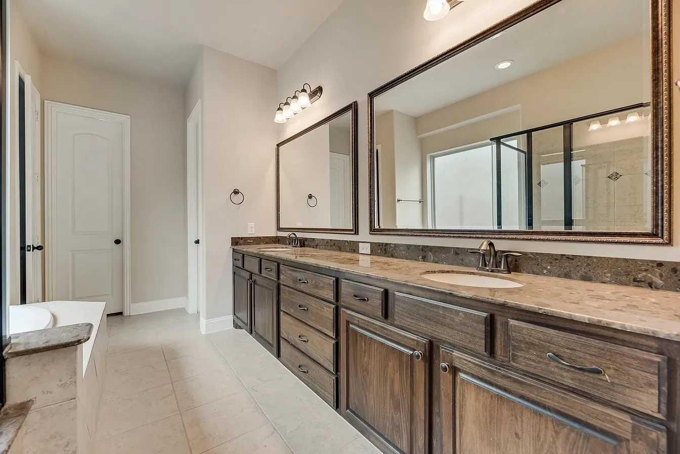 Dual vanity with wood-finish cabinetry, under-mount sinks, and stone countertops