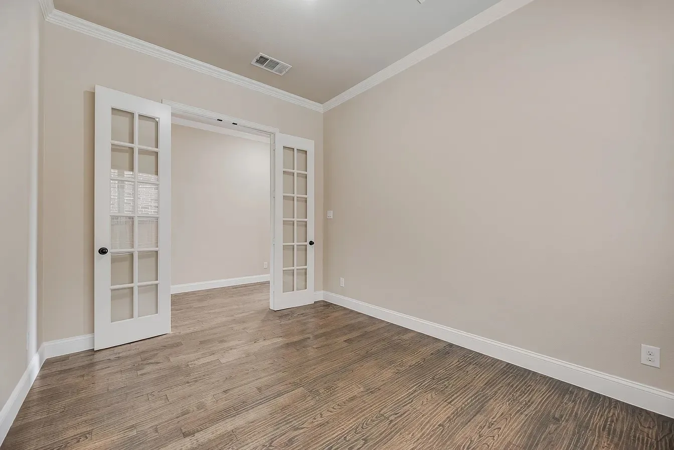 Interior room featuring wood-finish flooring, light neutral wall paint, and white crown molding