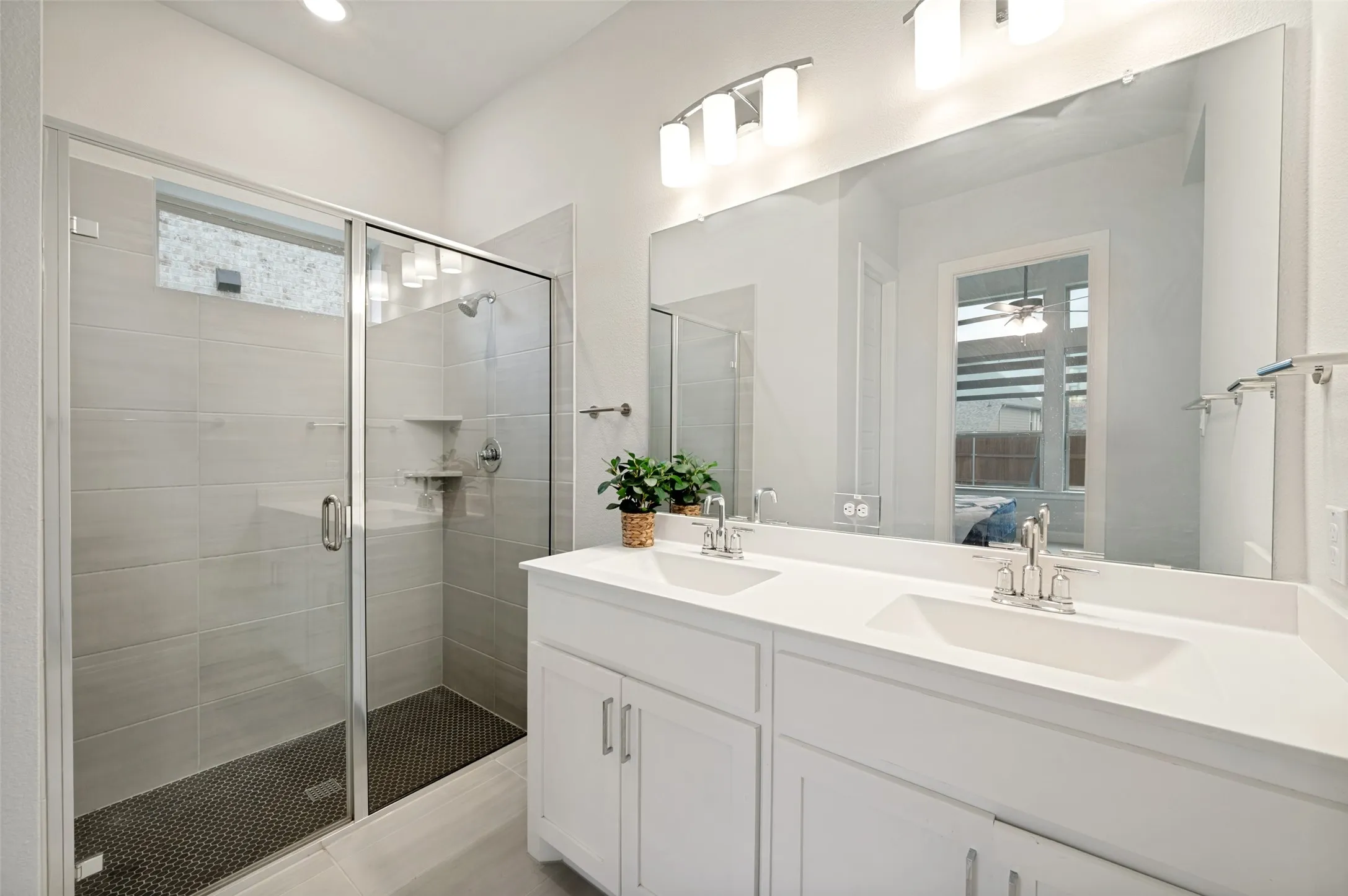Dual vanity with integrated sinks, a large frameless mirror, and modern light fixtures