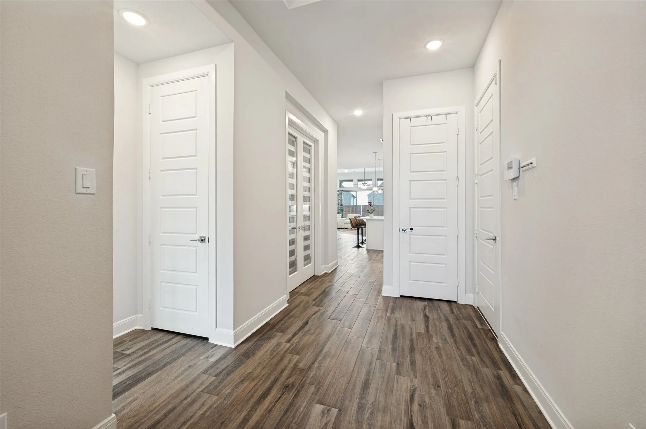 Hallway featuring wood-finish flooring, recessed lighting, shaker-style doors, and baseboard molding
