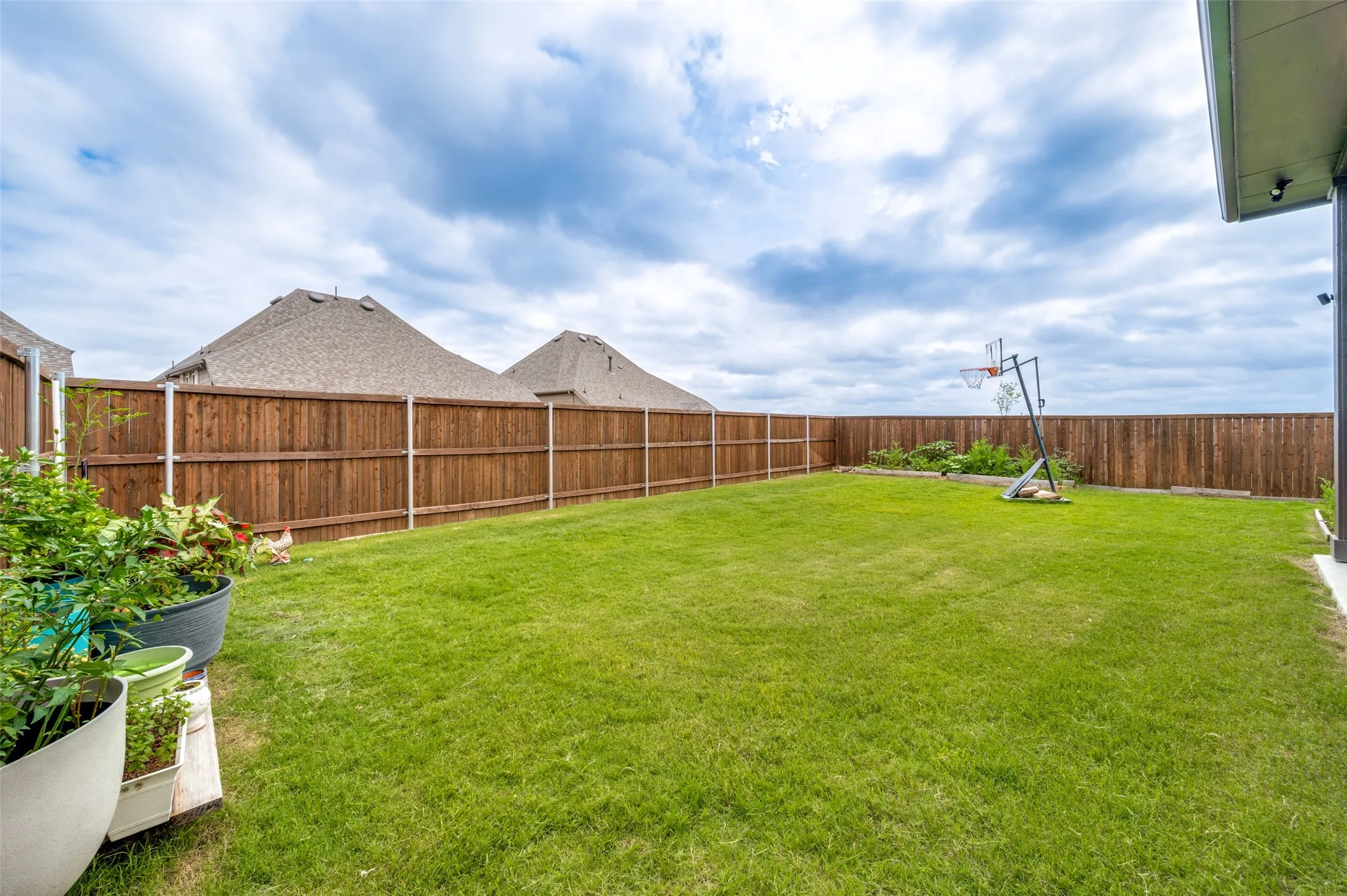 Expansive backyard featuring a lush lawn, privacy fencing, and a concrete patio section