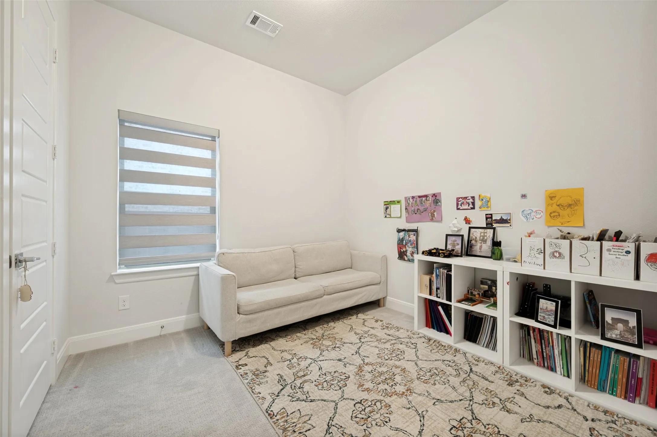 Carpeted room featuring a single window with blinds, white walls, and a modern door with paneling
