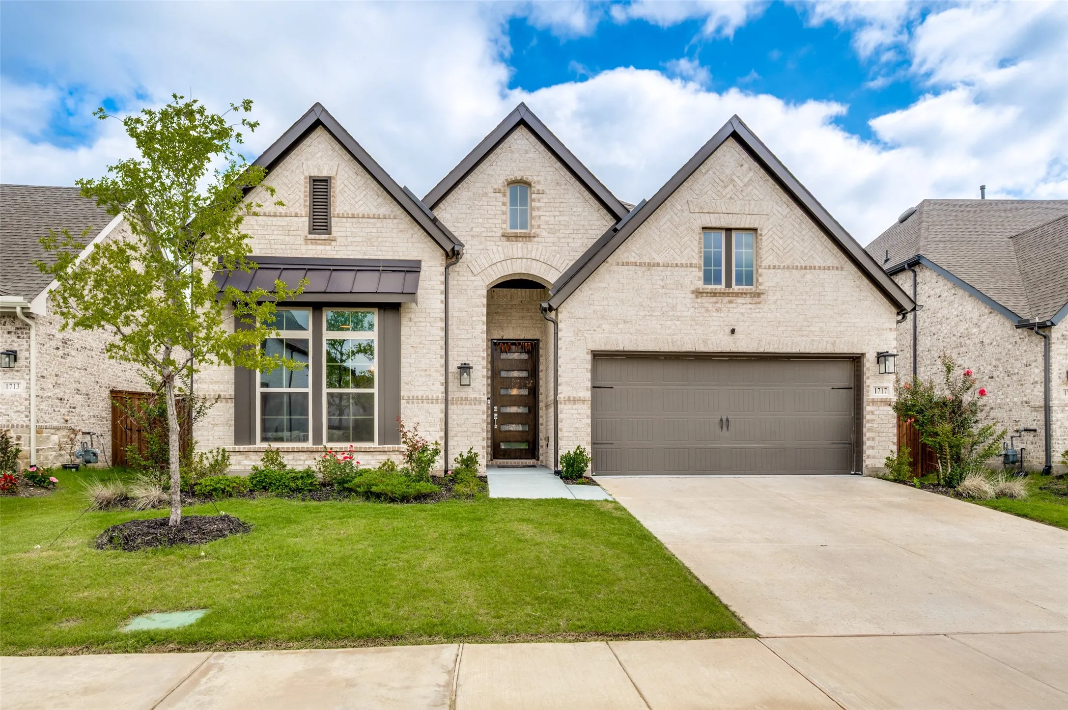 Contemporary brick residence featuring a two-car garage, established landscaping, and a substantial concrete driveway