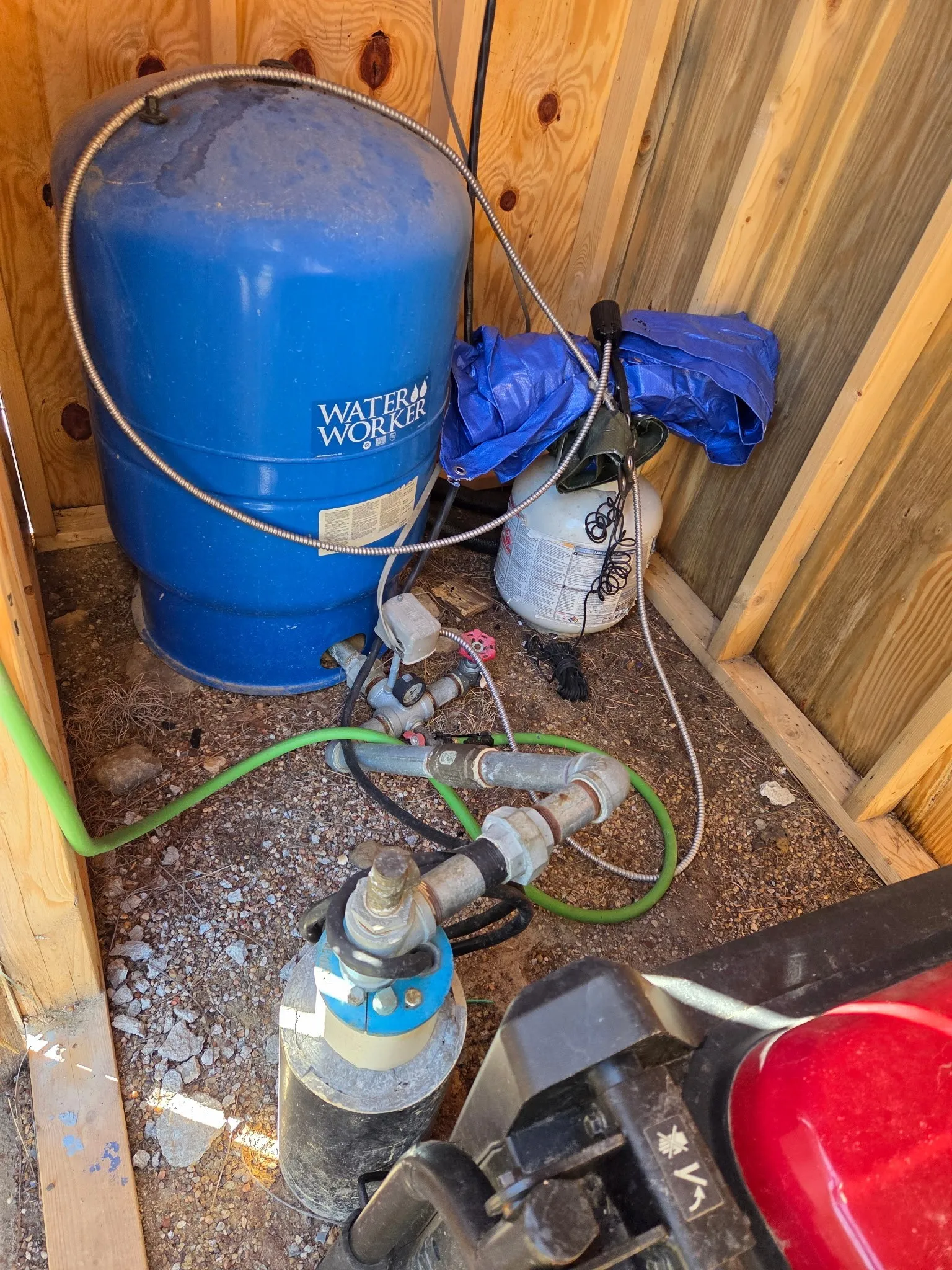Water pressure tank system with visible piping and connections within a wood-paneled utility enclosure