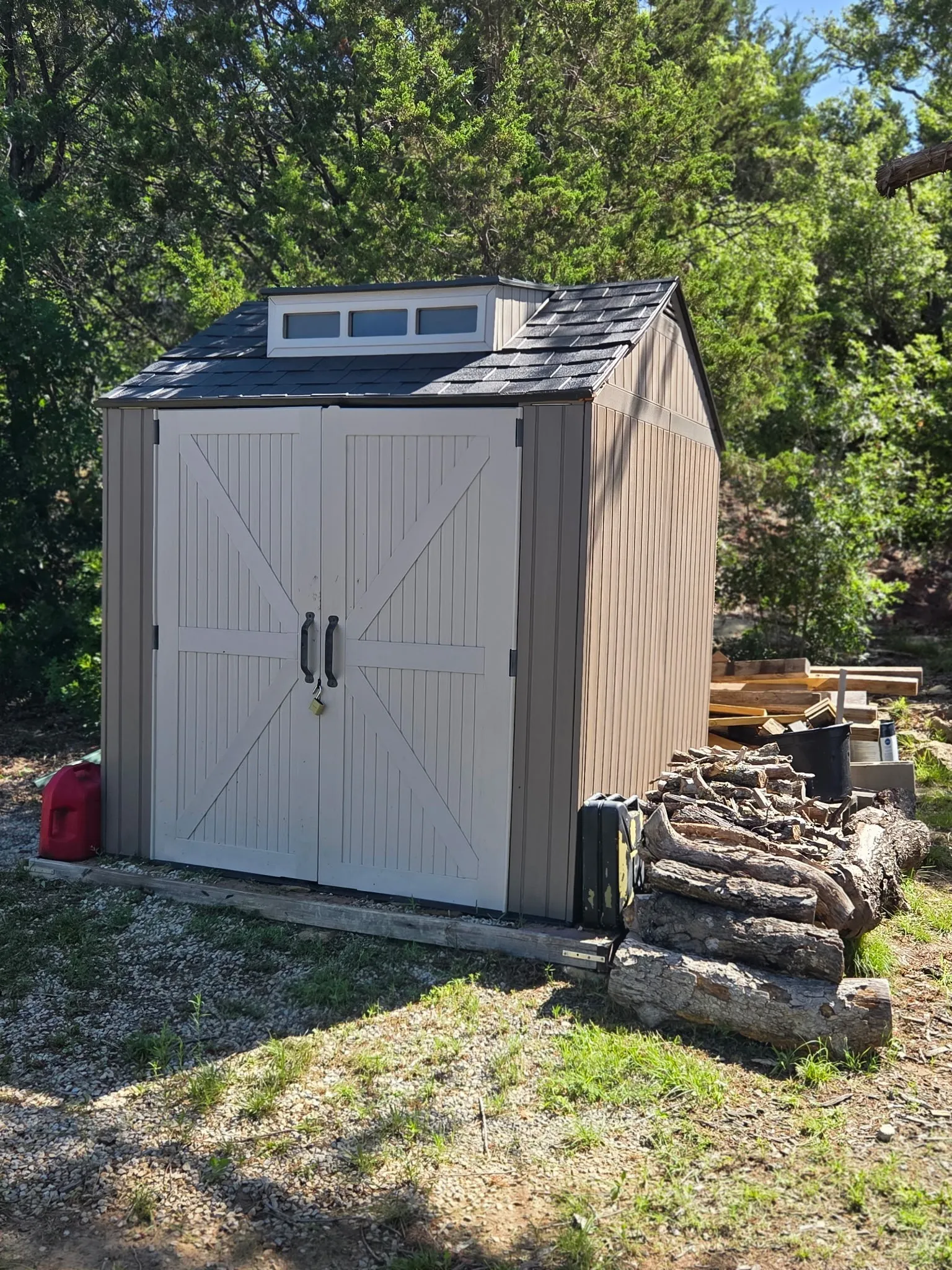 Outdoor storage shed with barn-style double doors, a durable shingle roof, and a skylight dormer
