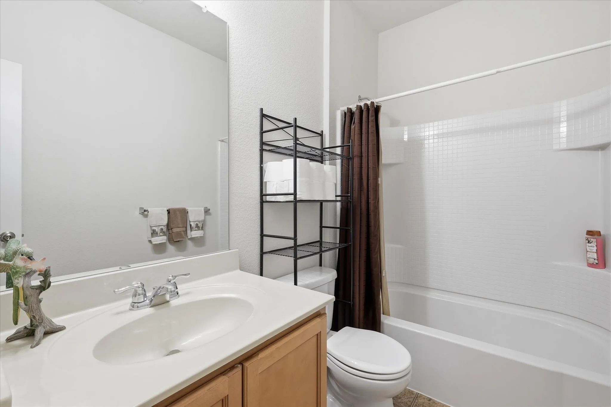 Bathroom featuring a single vanity with light-tone wood cabinetry, a white countertop, and a large wall-mounted mirror