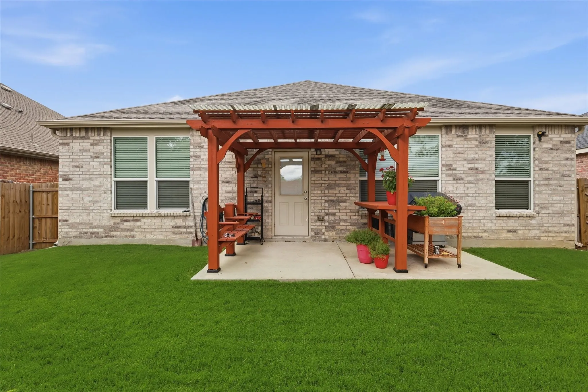 Expansive backyard featuring a red wood pergola over a concrete patio