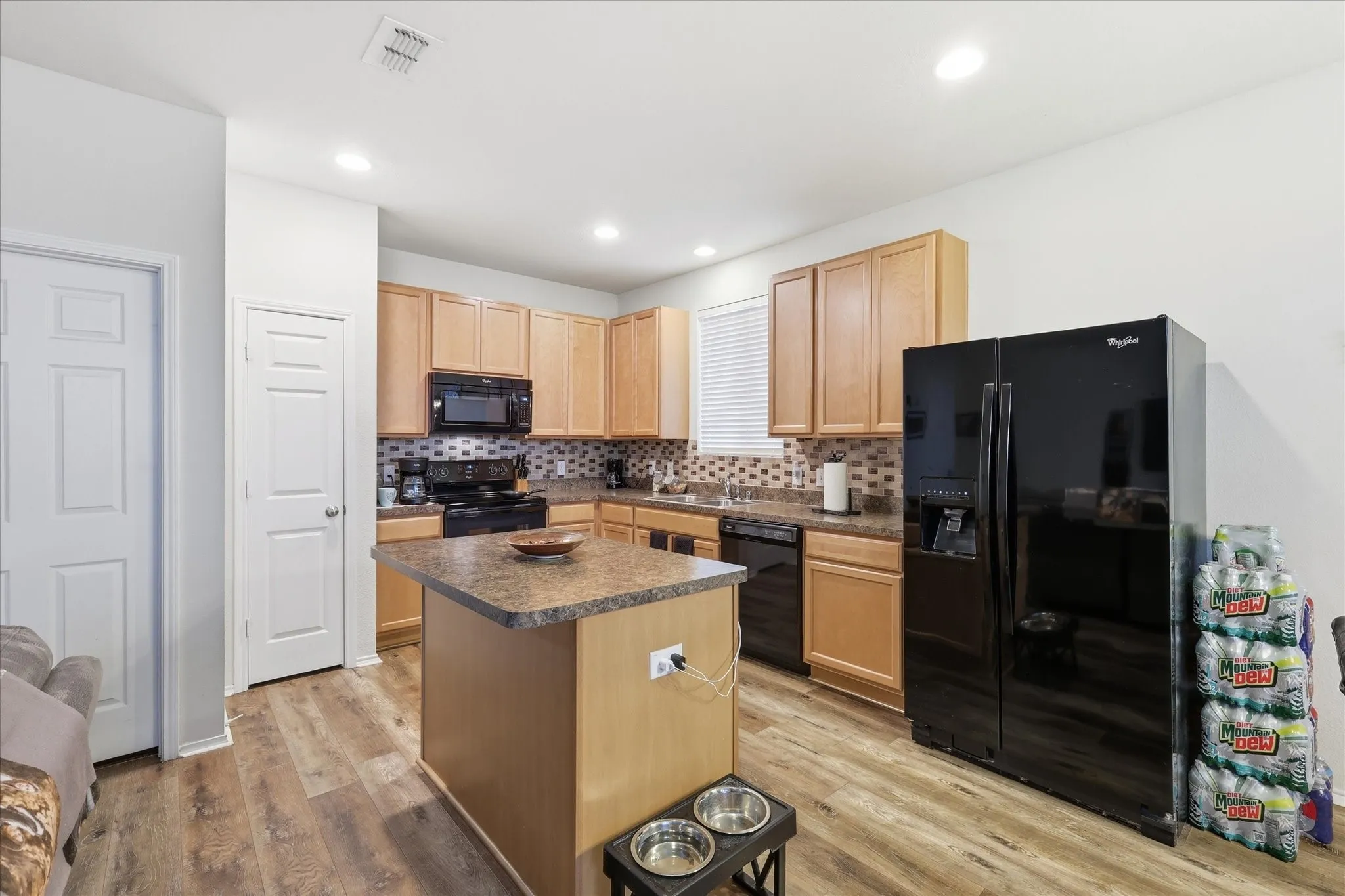 Kitchen featuring wood-finish flooring, recessed lighting, wood cabinetry, a center island with a stone-finish countertop, and a mosaic tile backsplash