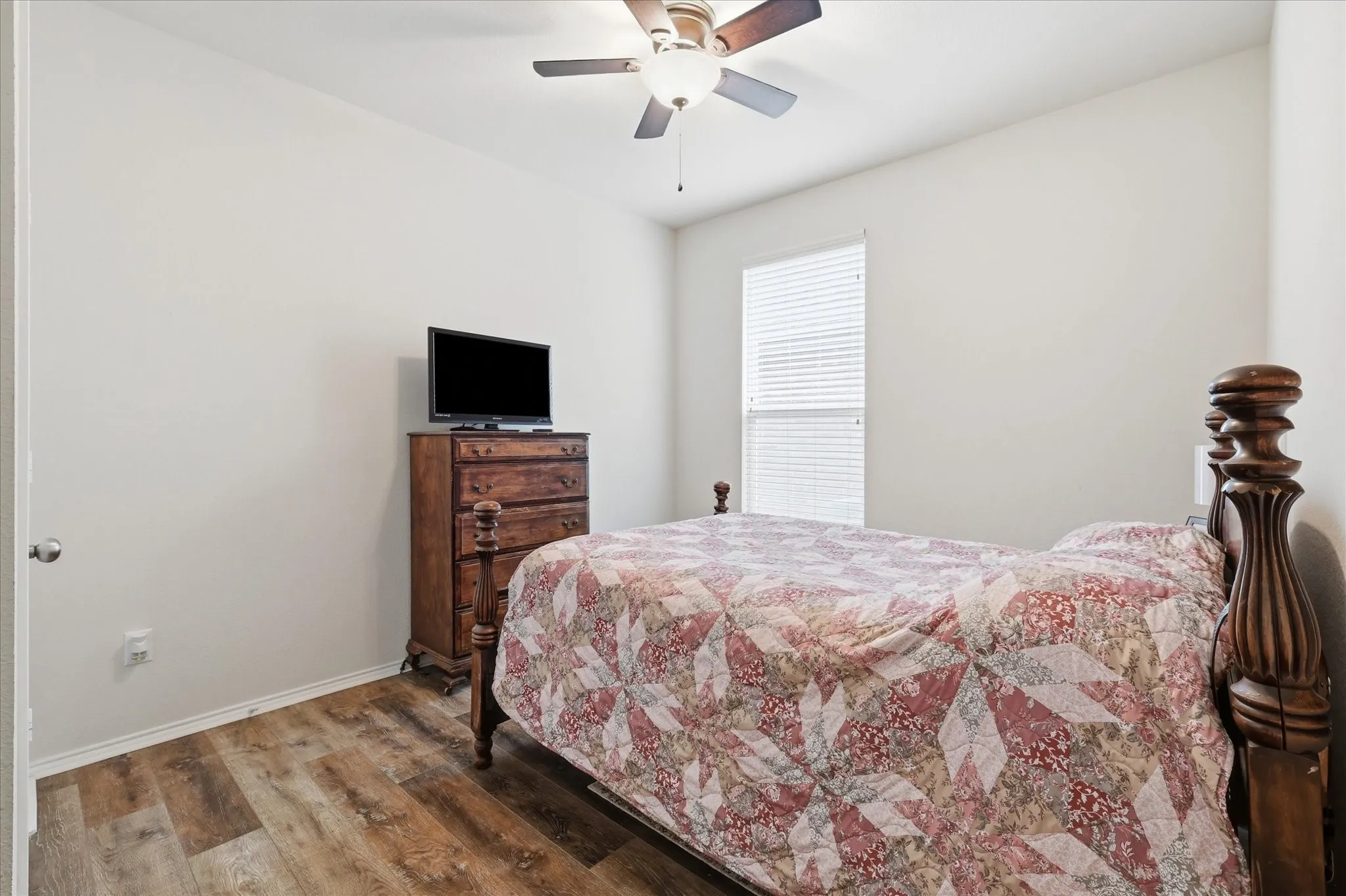 Bedroom featuring wood-finish flooring, a ceiling fan, and a window with horizontal blinds