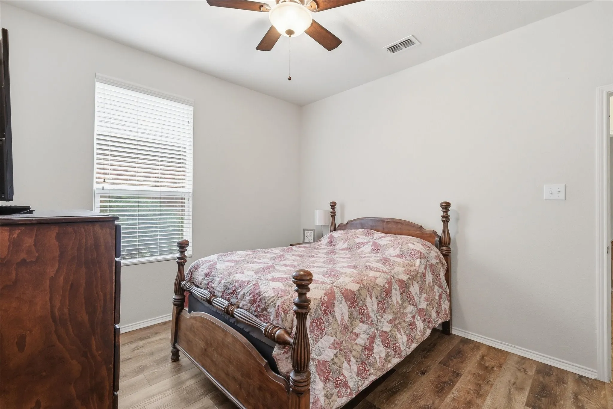 Room featuring wood-finish flooring, a window with blinds, a ceiling fan with integrated lighting, and neutral wall paint