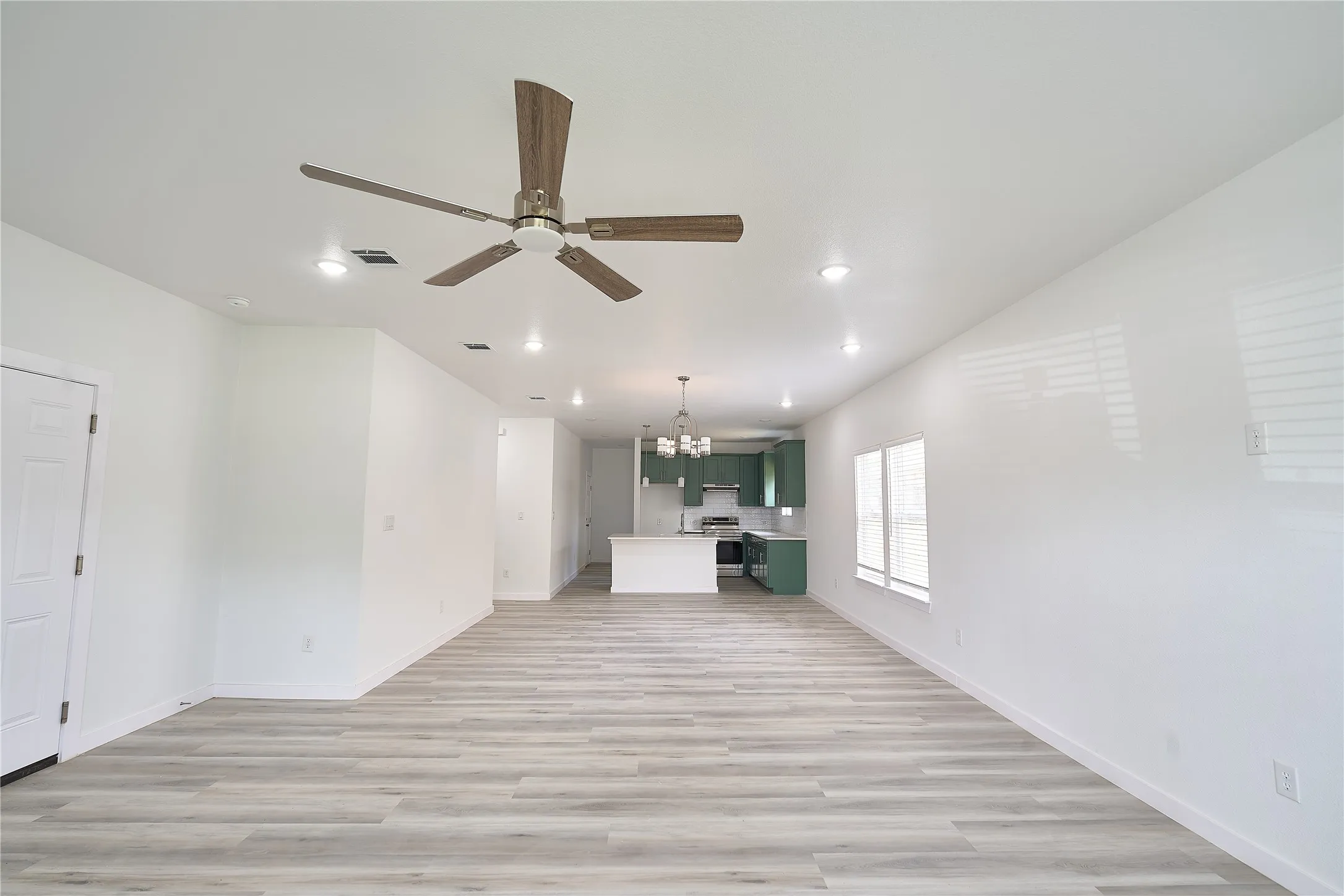 Open-concept living space featuring wood-finish flooring, a contemporary ceiling fan, and recessed lighting
