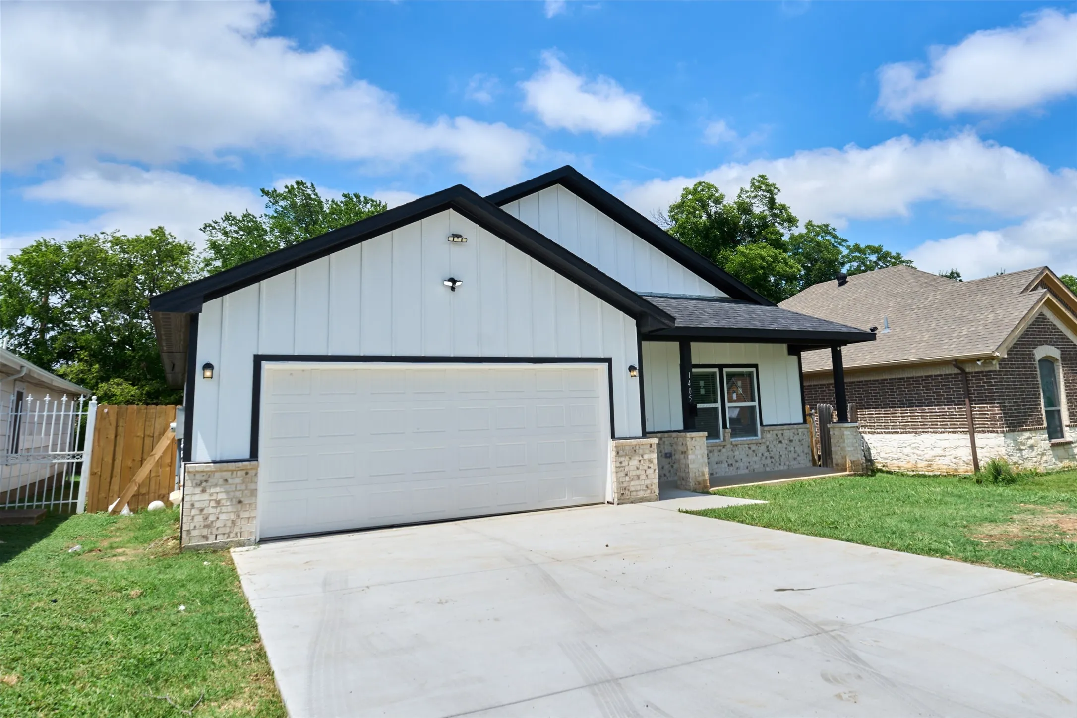 Contemporary exterior featuring white board and batten siding, dark trim, and a prominent two-car garage