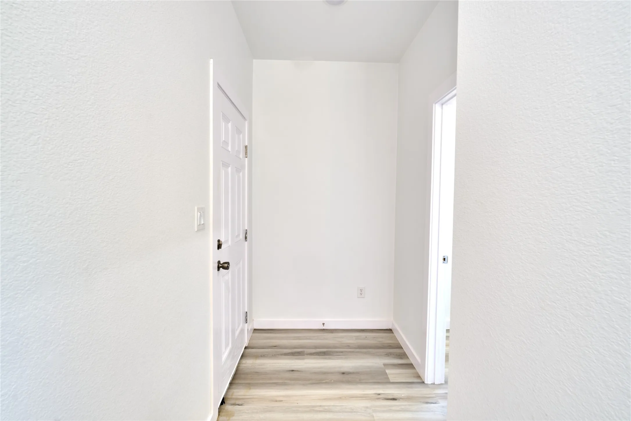 Entryway featuring wood-finish flooring, crisp white walls, and a recessed ceiling light