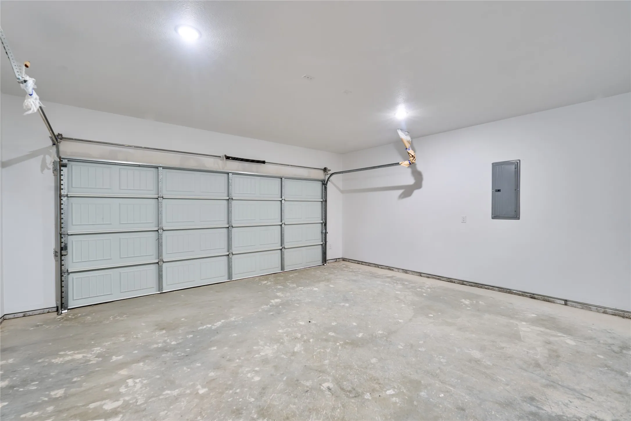 Two-car garage featuring a paneled overhead door, concrete flooring, and recessed ceiling lighting